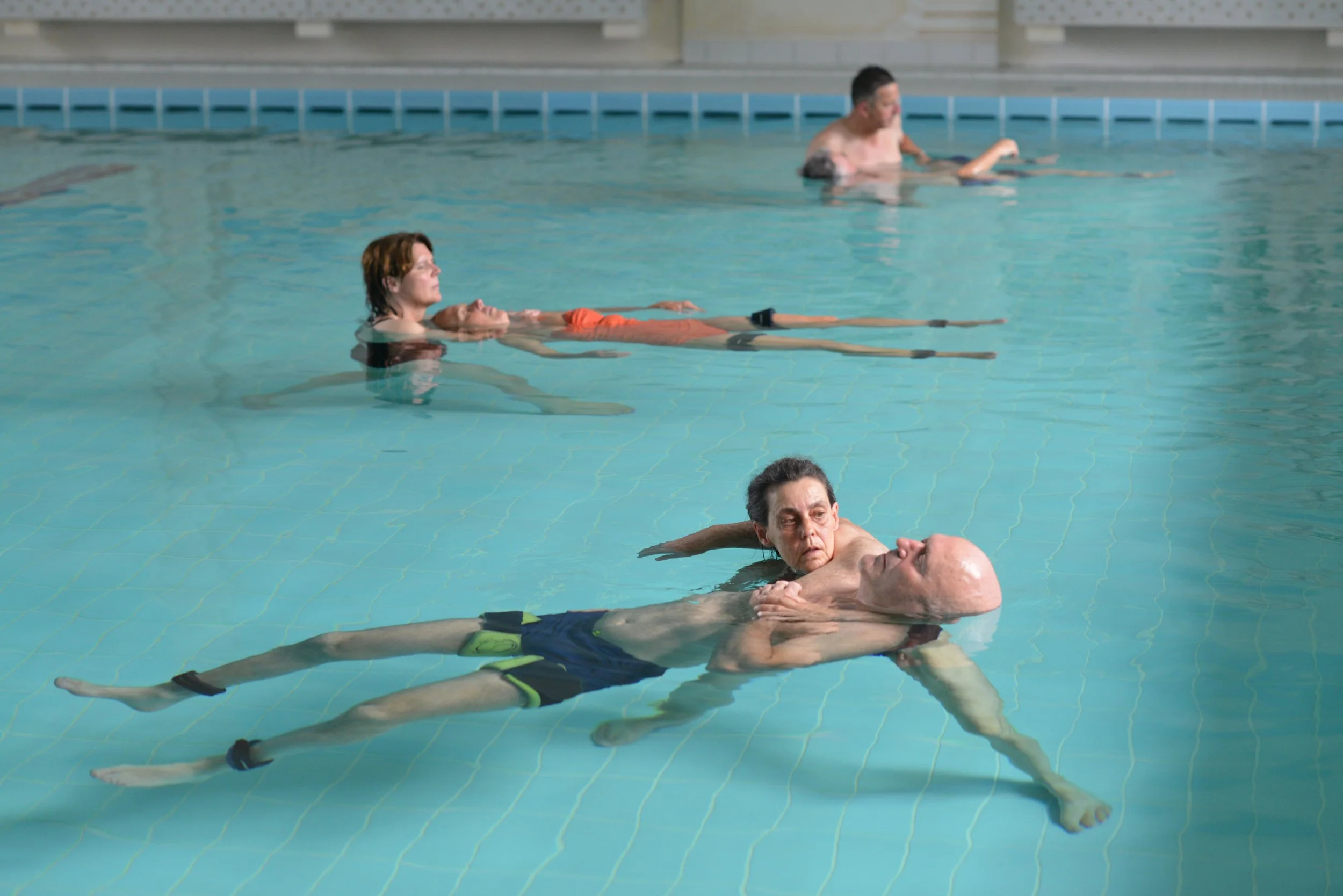 Menschen beim WATSU-Training im Becken, liegend auf dem Rücken im Wasser, mit geschlossenen Augen und entspannten Gesichtern.