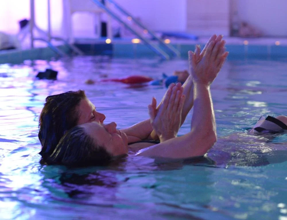 Ein Watsu-Schülerin des Aquamunda Instituts gibt einer anderen Schülerin eine Session und dehnt ihre Arme.