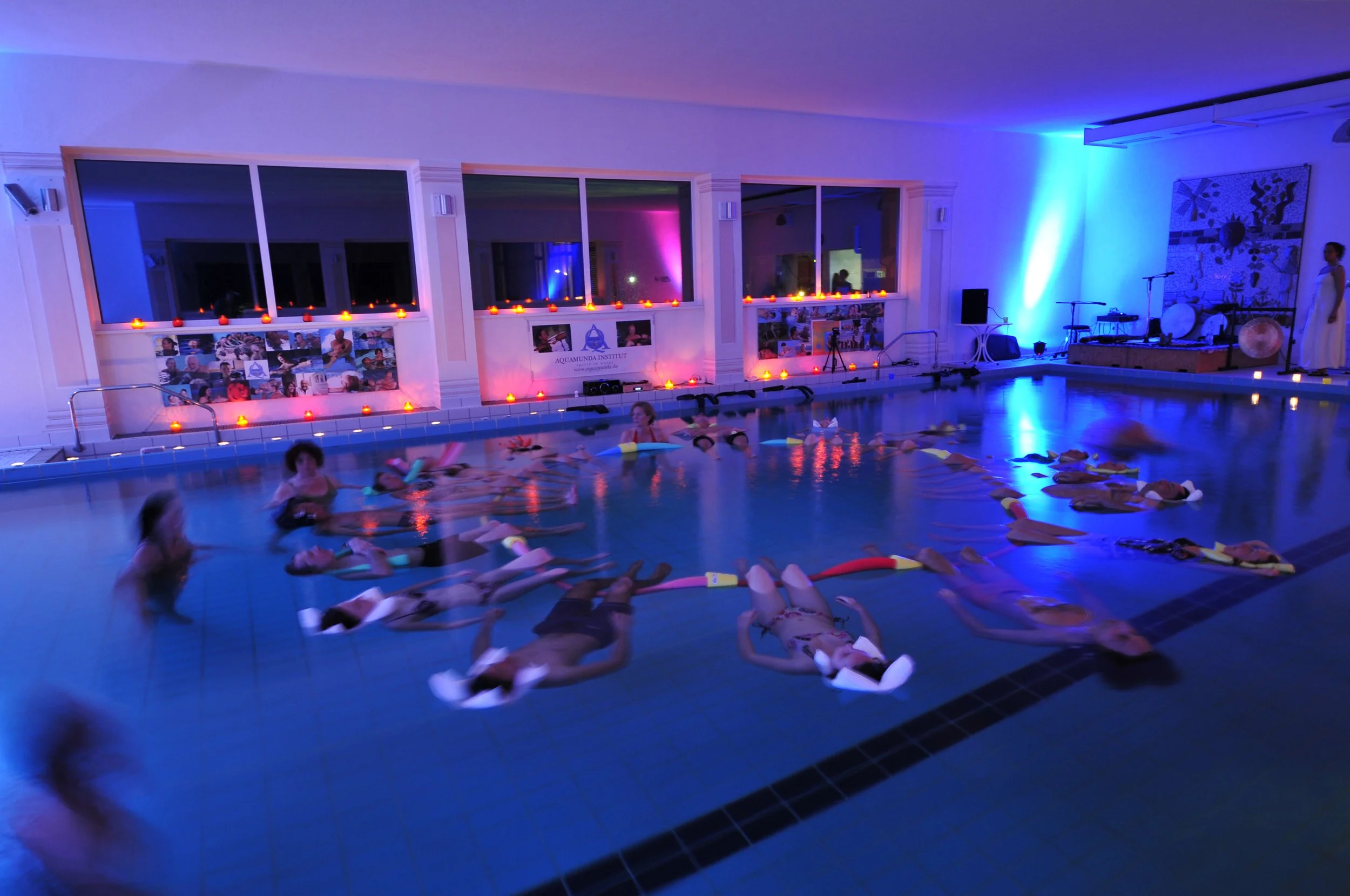 Menschen liegen entspannt gehalten von Poolnudeln und Wasserkissen im warmen Wasser bei der Aquatischen Nacht in Kißlegg.
