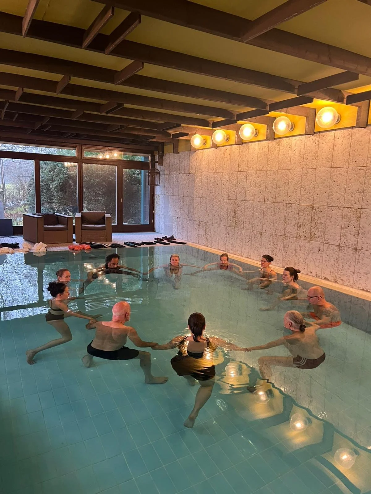 Ein Gruppe von Watsu-Schülern bilden im Wasser einen Kreis und halten sich dabei an den Händen. Einleitung eines Aquamunda Watsu-Seminars