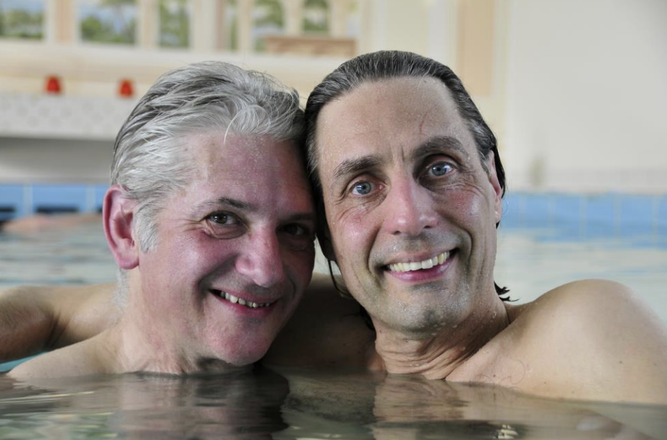 Paul (links) mit Gary (rechts) in freundschaftlicher Umarmung schauen in die Kamera und lächeln