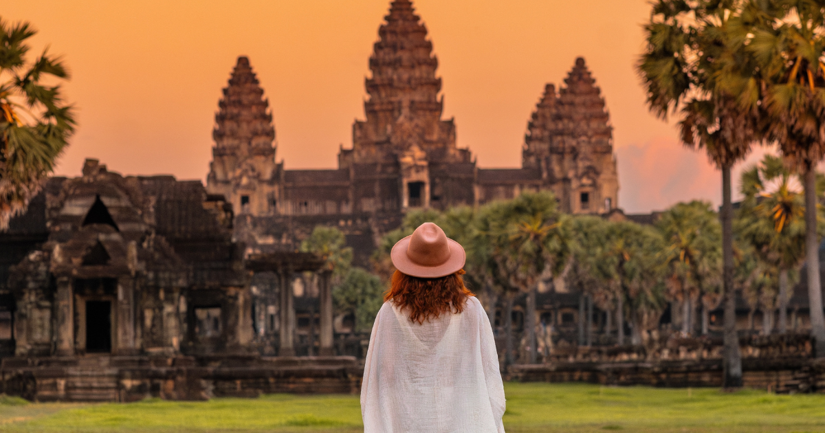 Visitor standing outside Angkor Wat at sunrise with the temple towers in the background