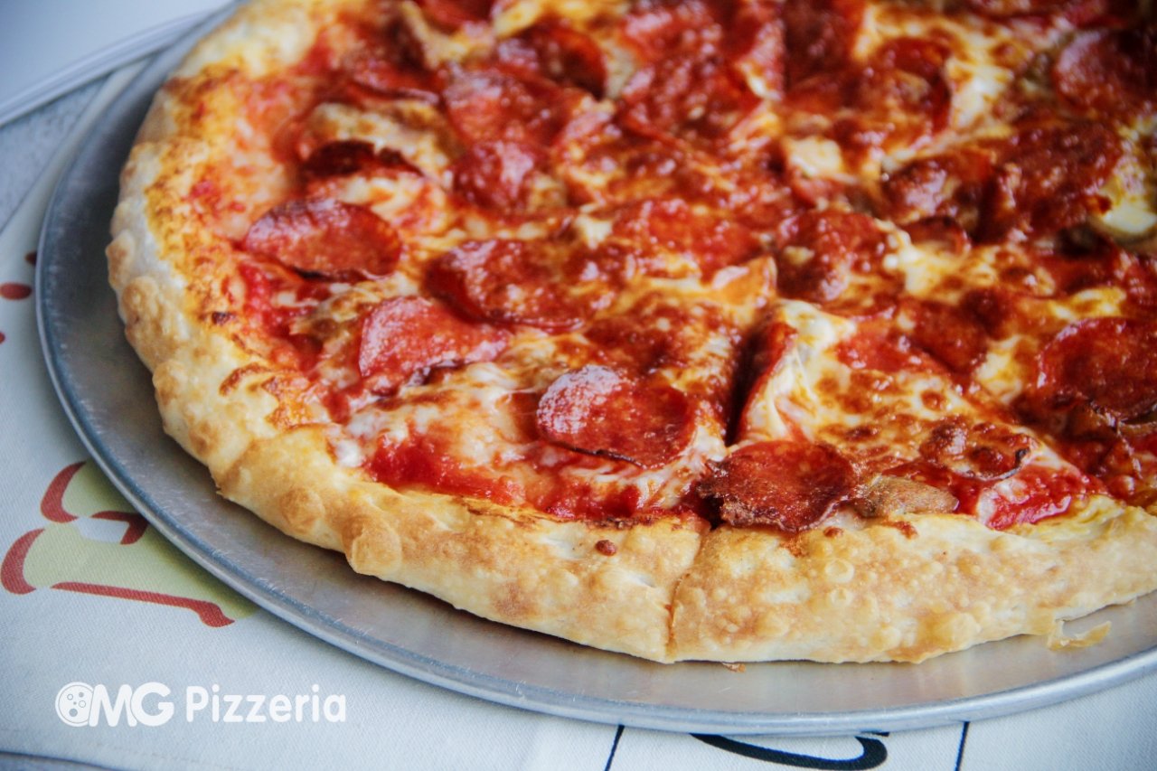 Close-up of a pepperoni pizza on a metal tray, with melted cheese and tomato sauce.