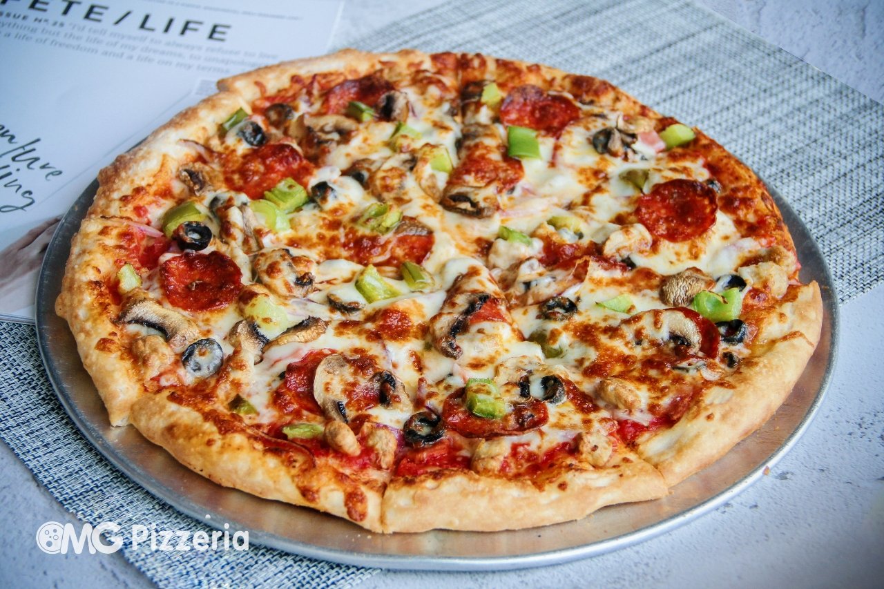 A pizza with pepperoni, green peppers, mushrooms, black olives, and melted cheese on a metal tray.