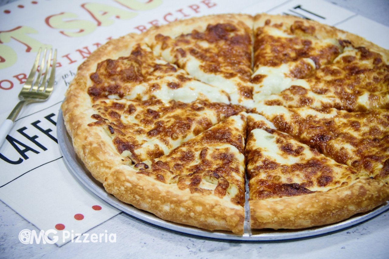 A cheese pizza with a golden crust on a metal tray on a white tablecloth with a fork nearby.