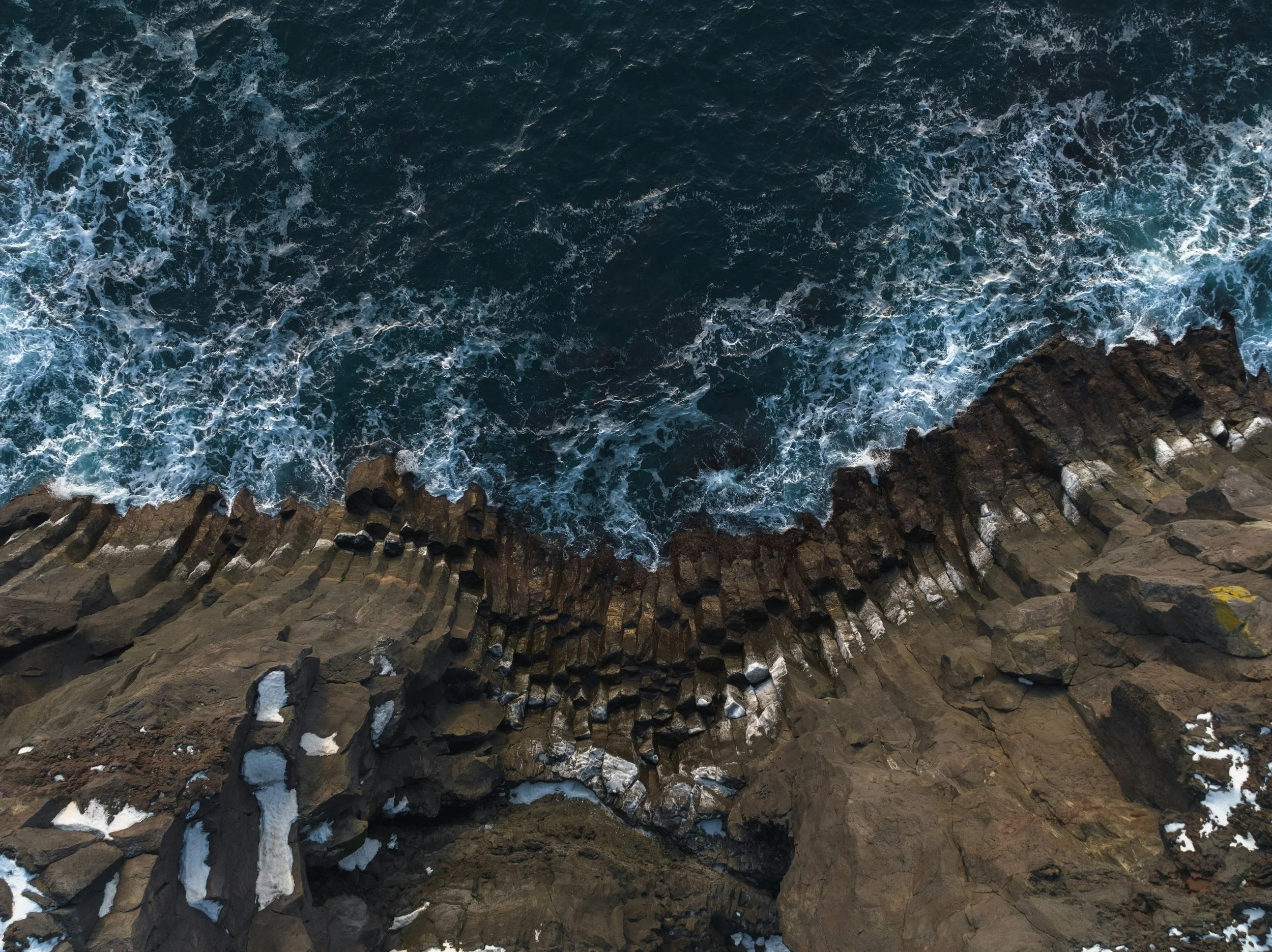 Aerial view of rocky coastline with crashing ocean waves