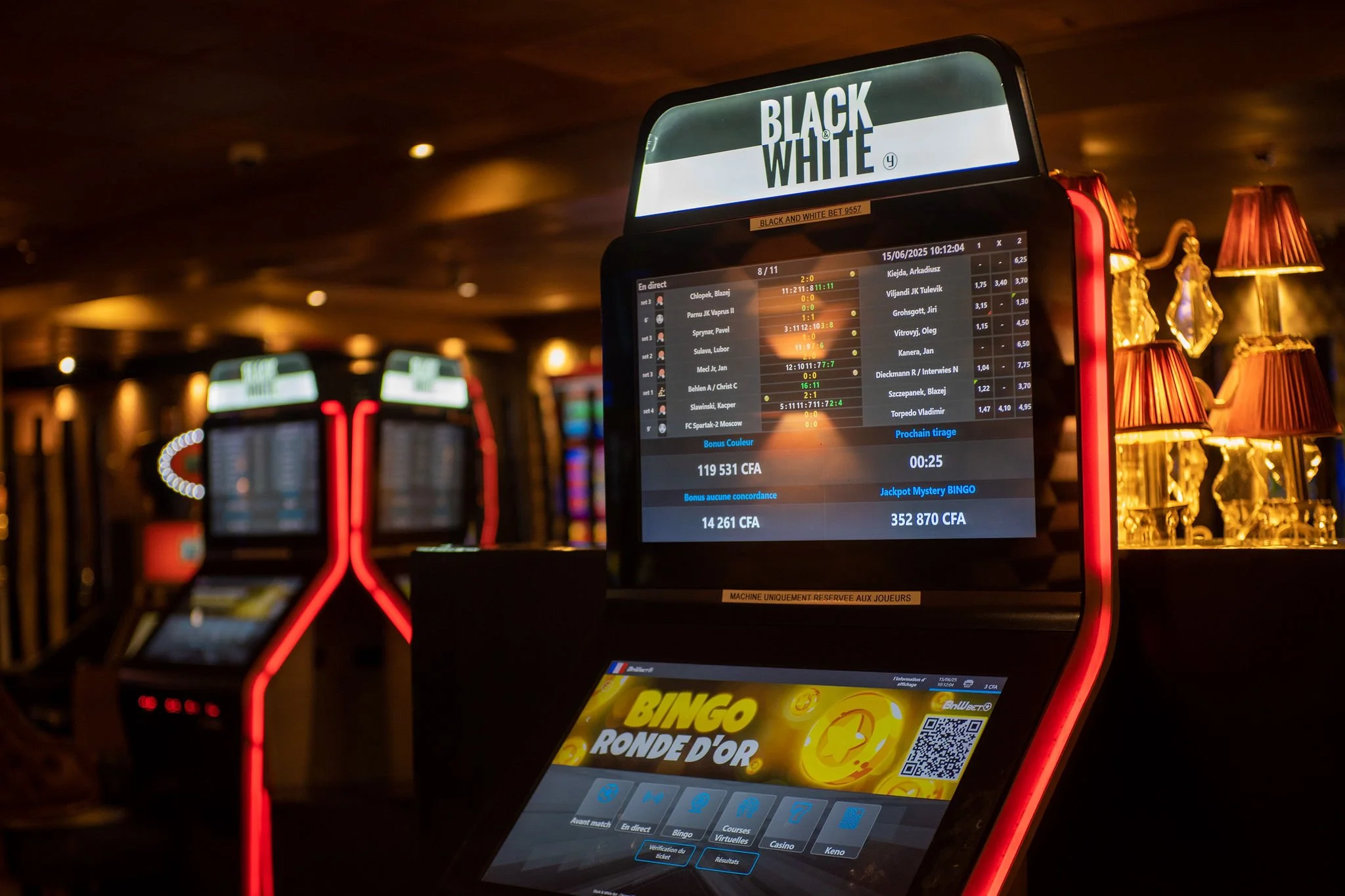 Electronic gaming machines in a casino with illuminated screens and red lighting accents.