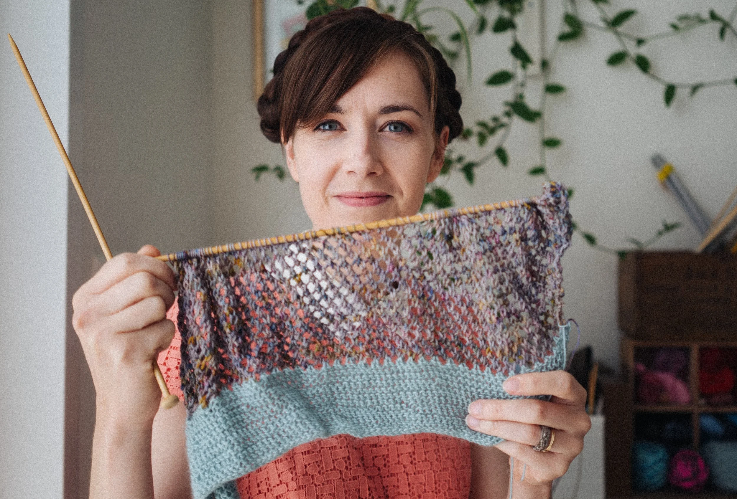 Alice, a white female knitting teacher holds up lace knitting