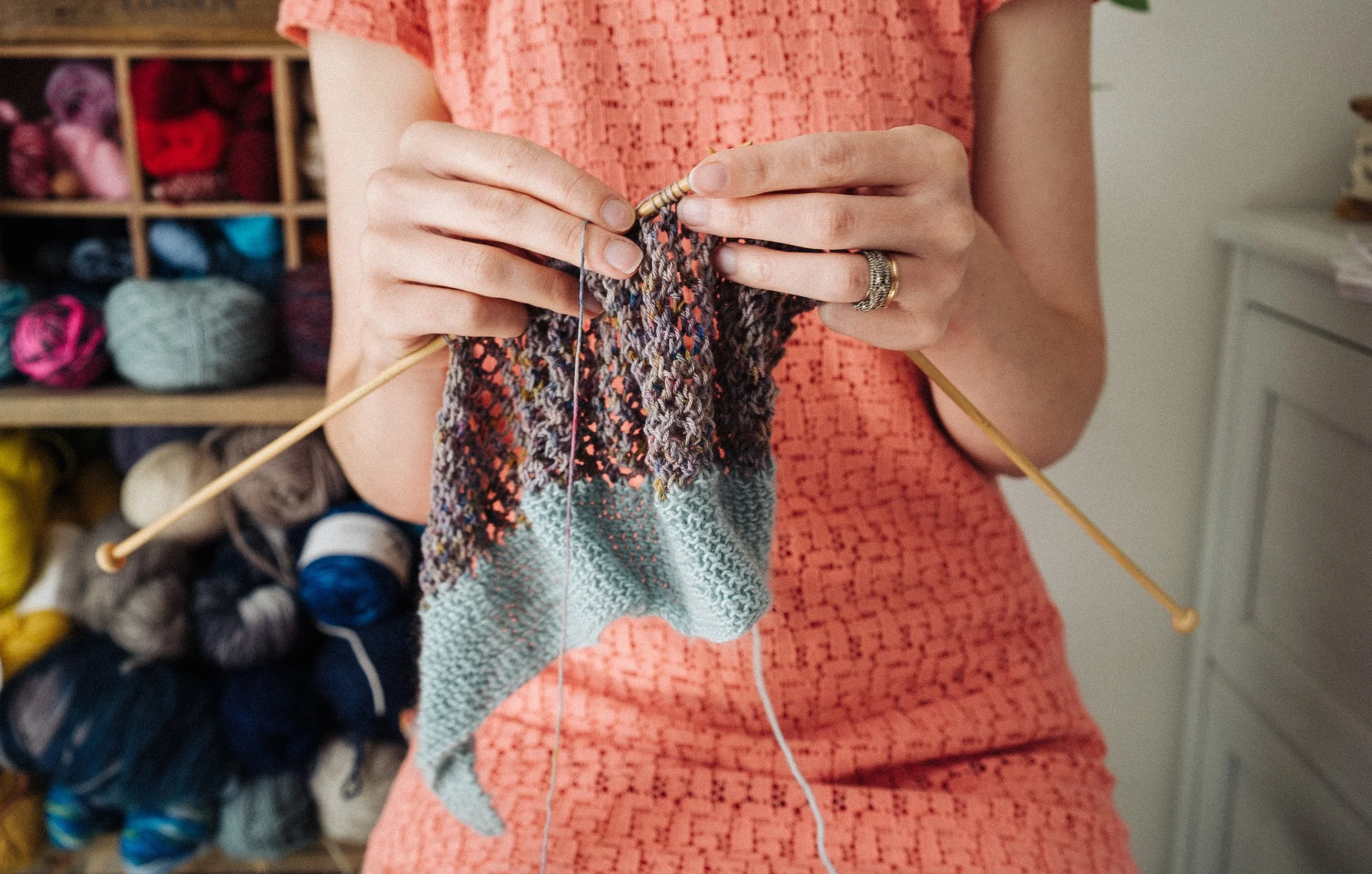 Knitting Teacher Alice knits with purple and blue yarn wearing a peach dress