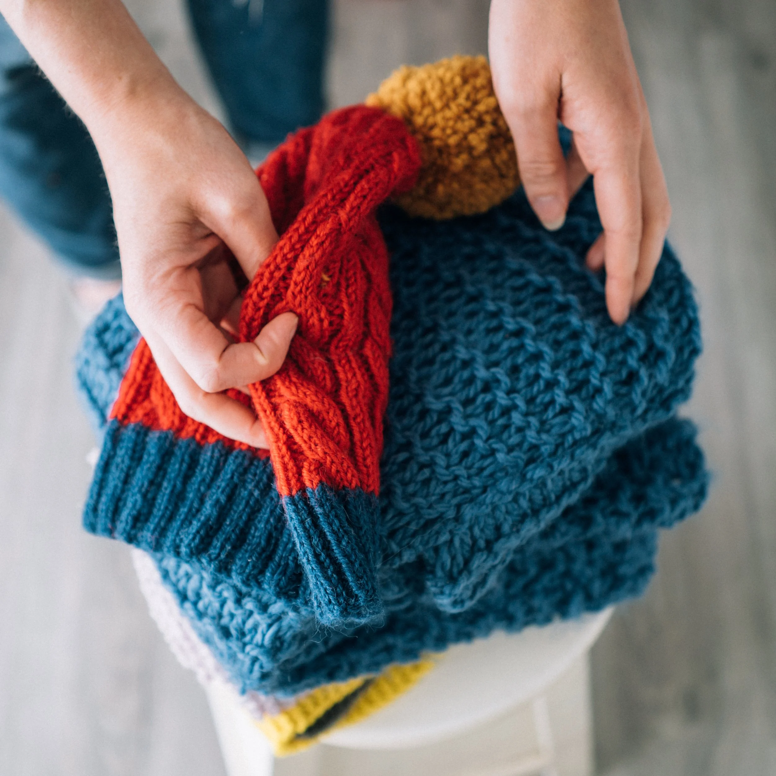 Knitting Teacher Alice's hands look through a stack of knitted pieces