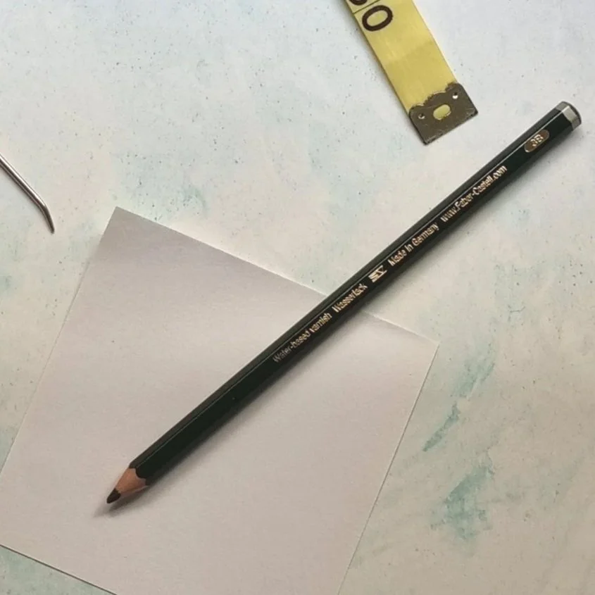 A pencil lays on a small piece of white paper