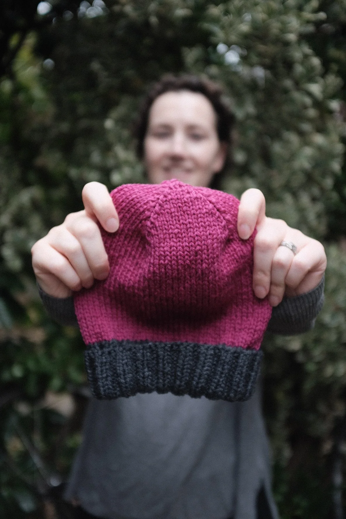 Knitting Teacher Alice holds out a pink and grey colour blocked beanie hat