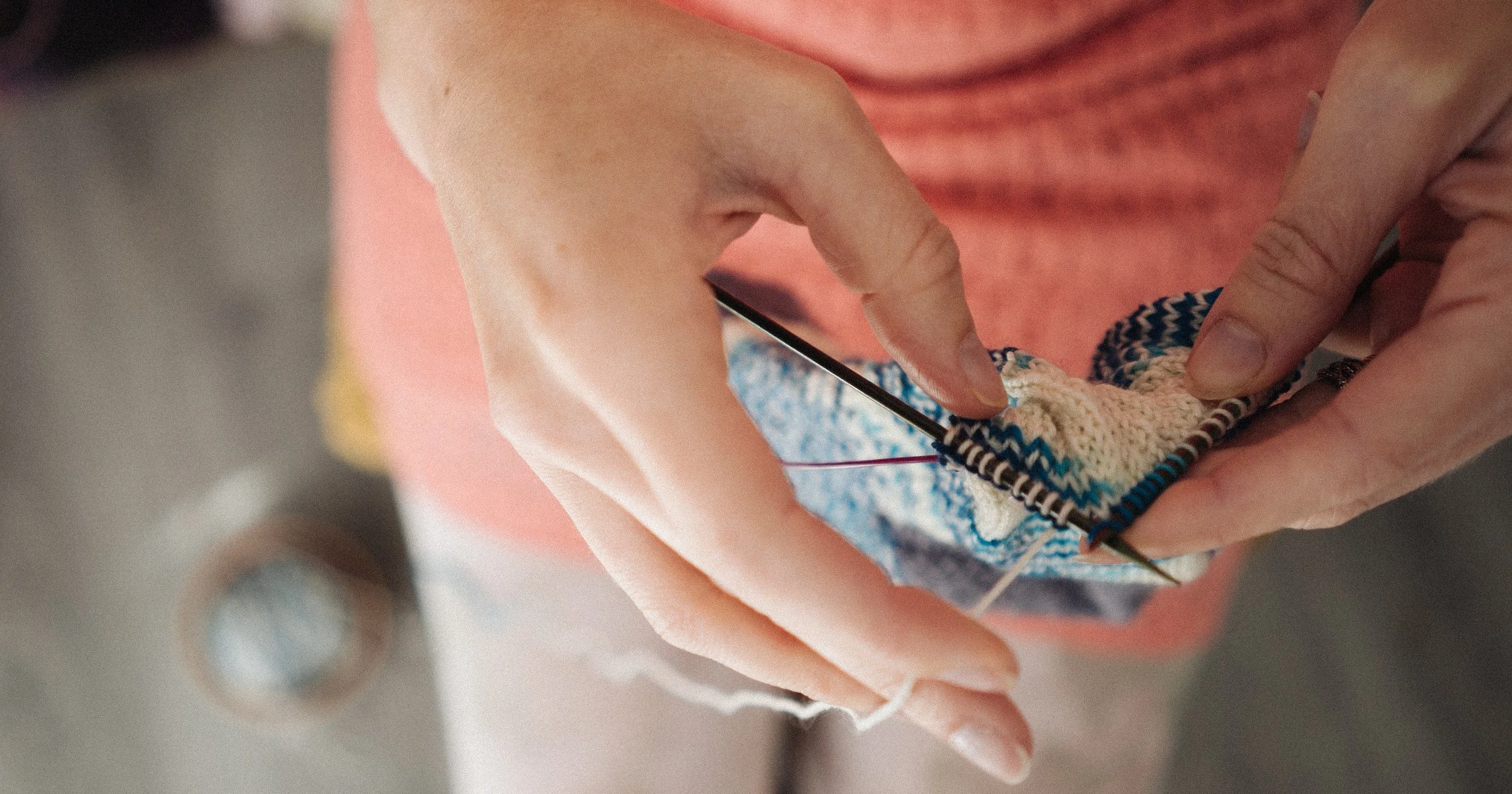Knitting teacher Alice knits socks with cream and blue yarn