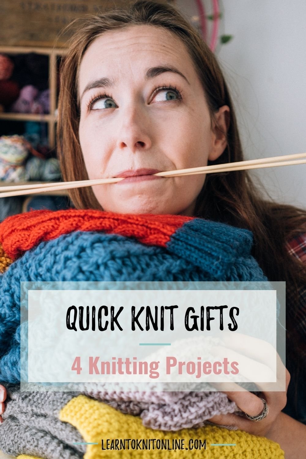 White woman with a pile of handknits and wooden needles in her mouth