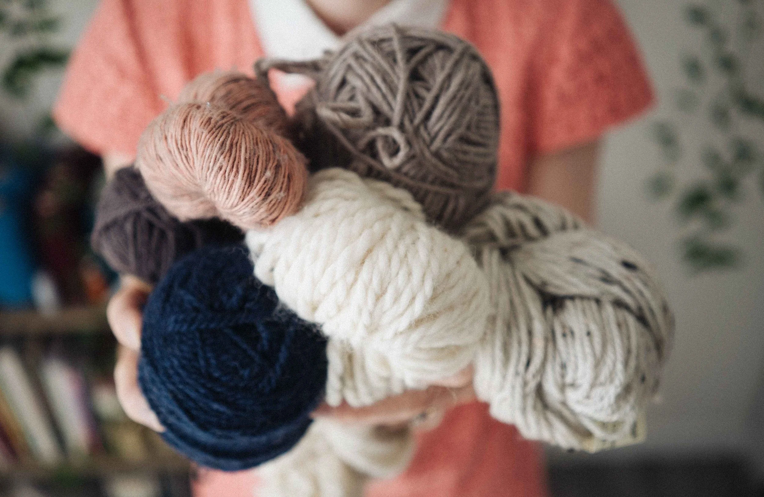 Alice, a knitting teacher holds out a bundle of different knitting yarns