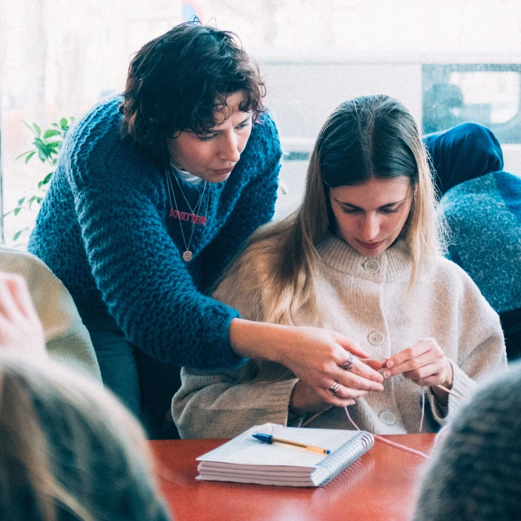 Knitting Teacher Alice helps a beginner knitter in a knitting class
