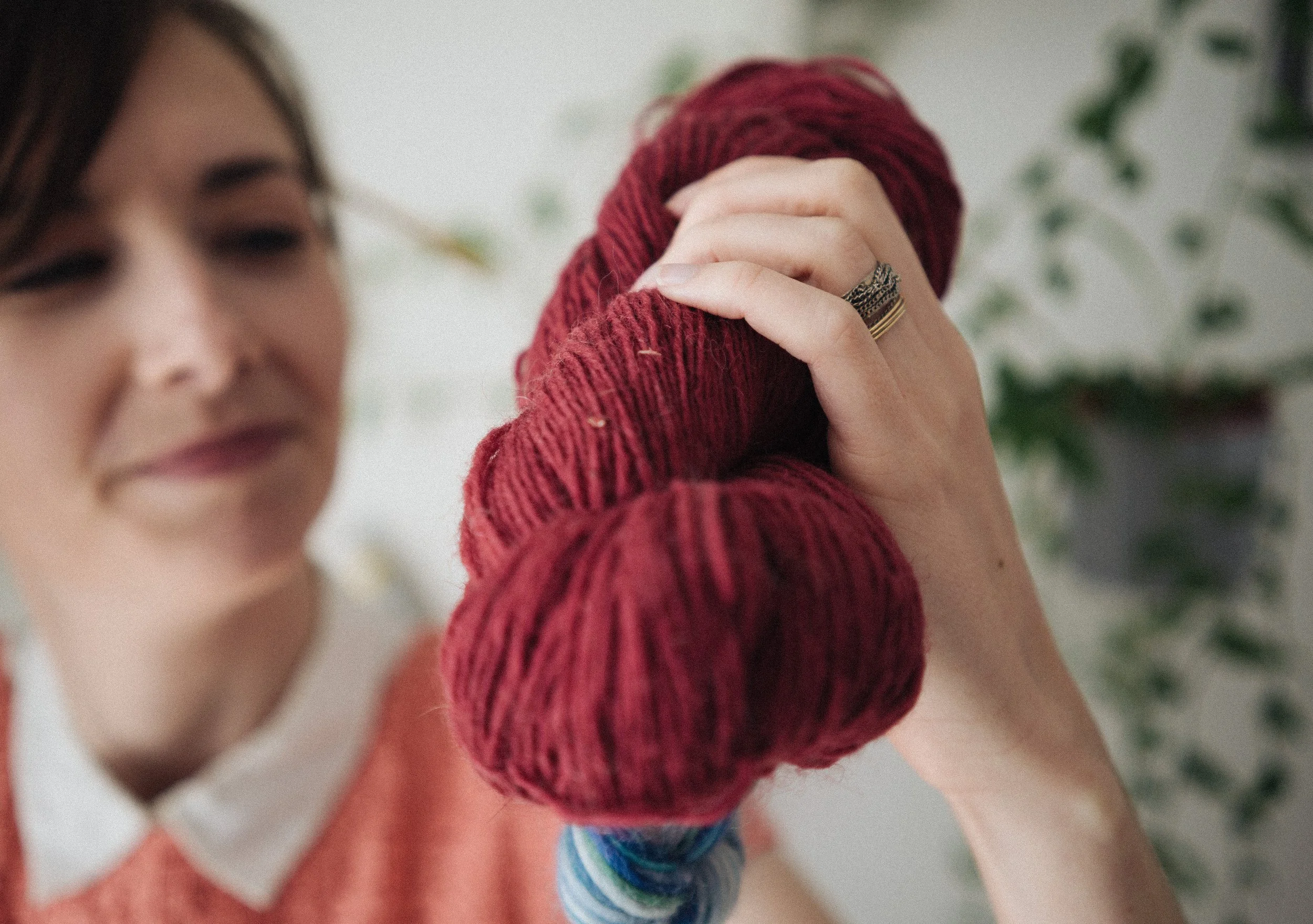Alice a white female knitting teacher holds a skein of marroon red yarn in her hand