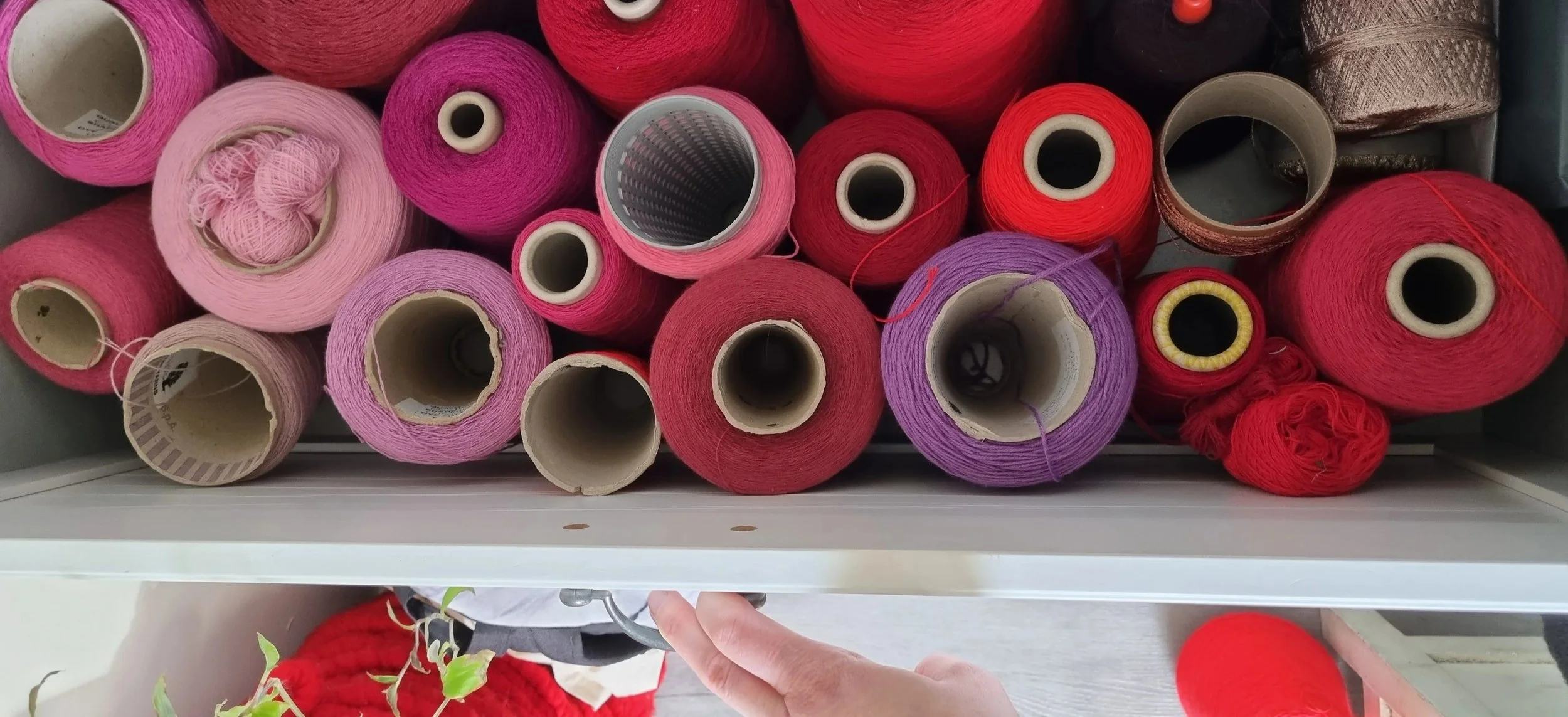 A drawer full of red cones of yarn
