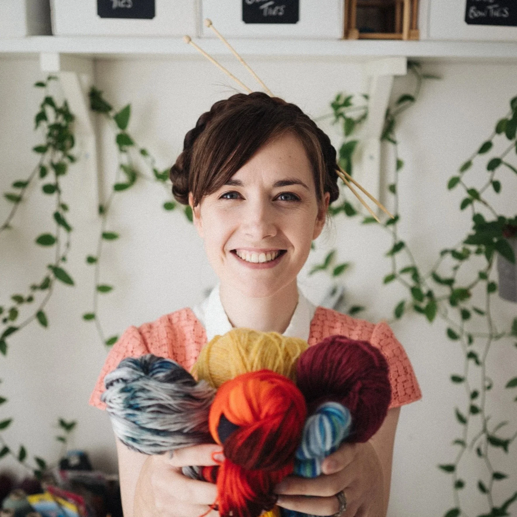 Knitting Teacher Alice, a white woman holds out yarn while smiling