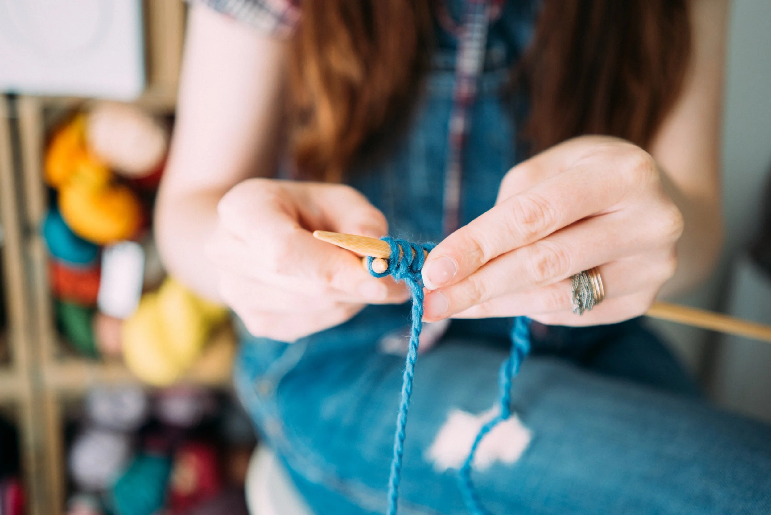 Knitting Teacher Alice knits with blue yarn on wooden needles