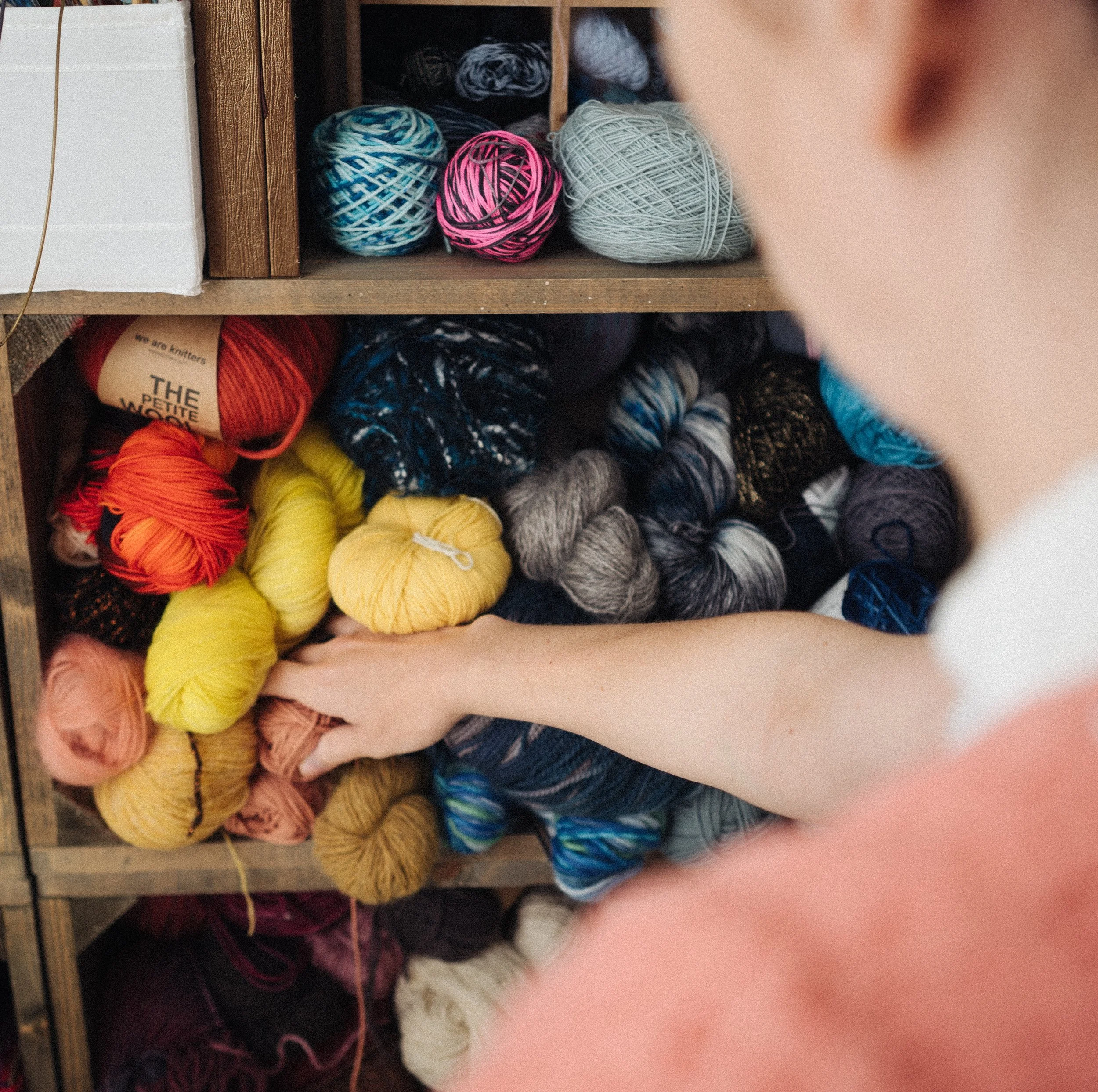 Alice a knitting teacher reaches into a crate of yellow and orange yarns