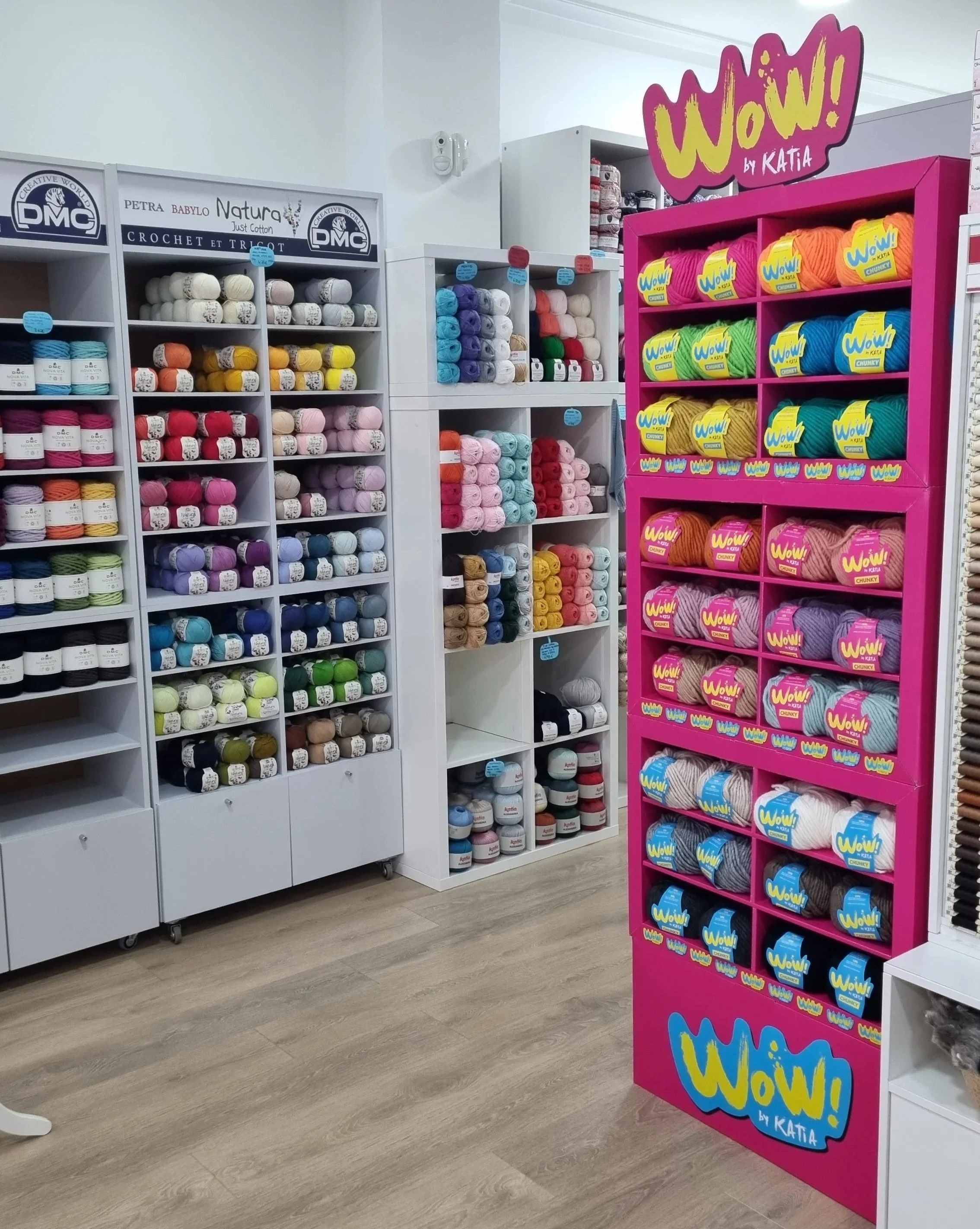 Knitting yarn displayed in pink and white shelving in a yarn store