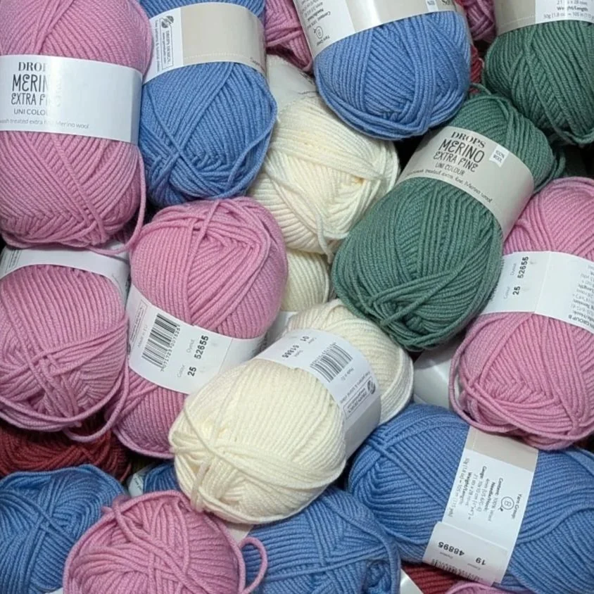 A collection of Merino yarn balls in blue, pink, green and cream