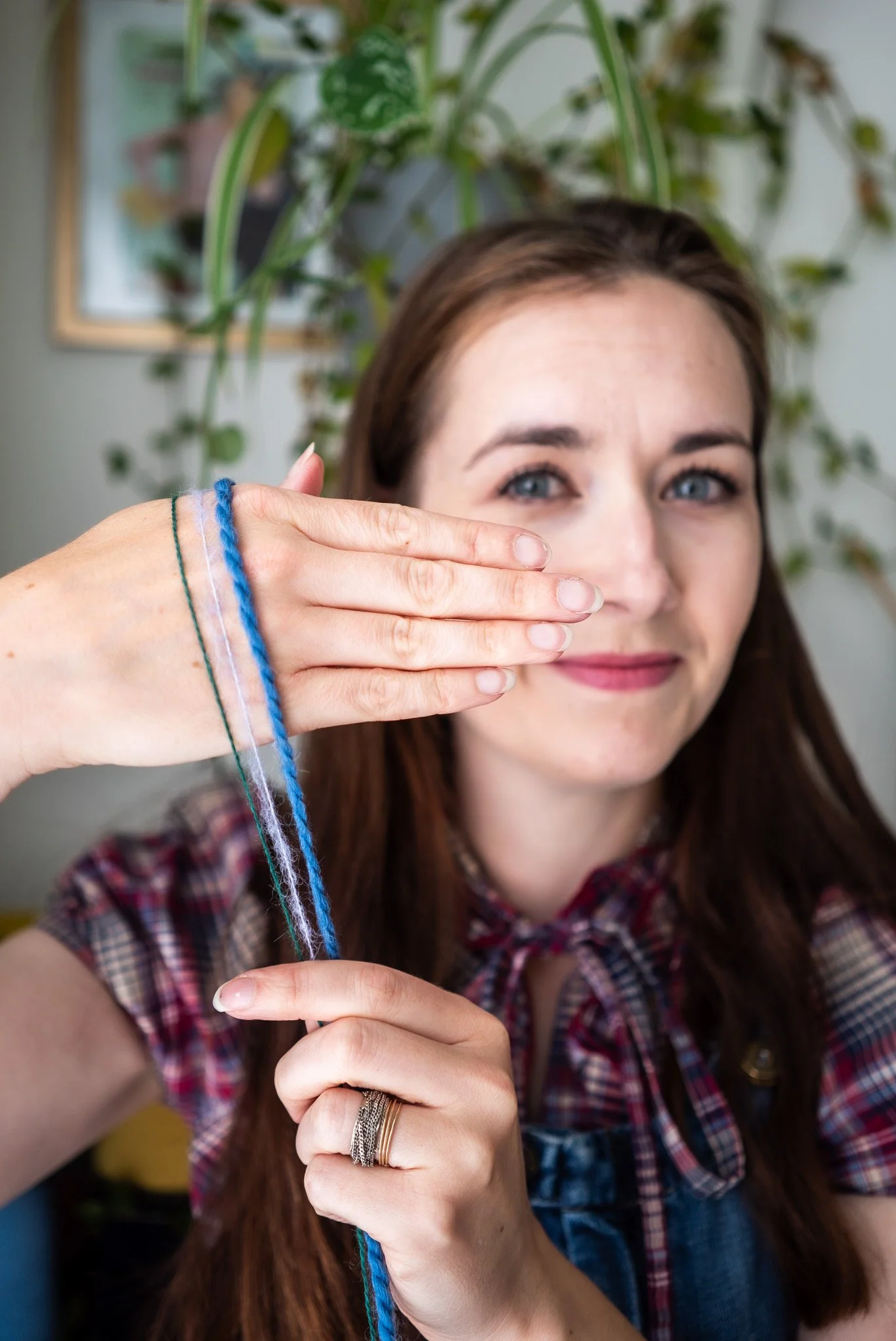 Knitting Teacher Alice holds 3 different thickness knitting yarns against the back of her hand as she smiles