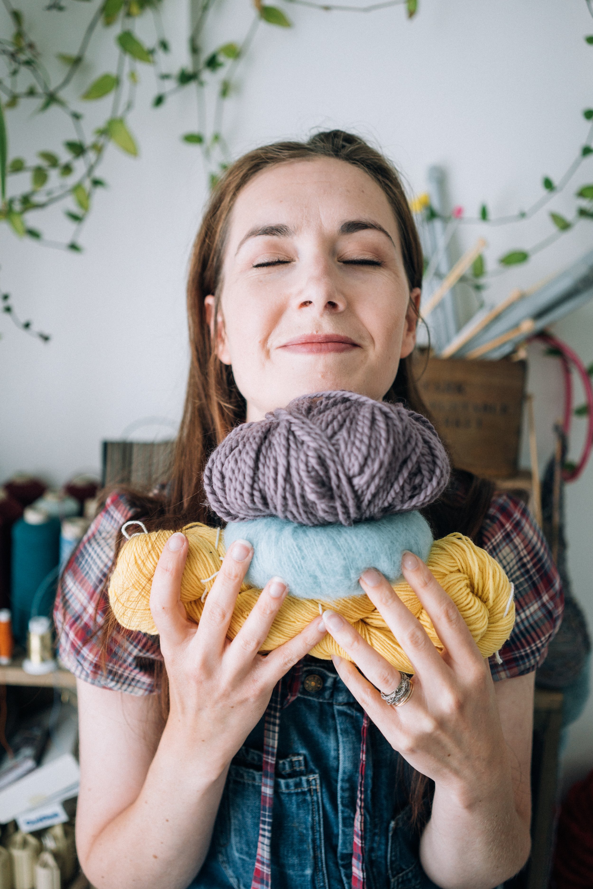 Knitting Teacher Alice holds a stack of different colour yarn with her eyes closed peacefully
