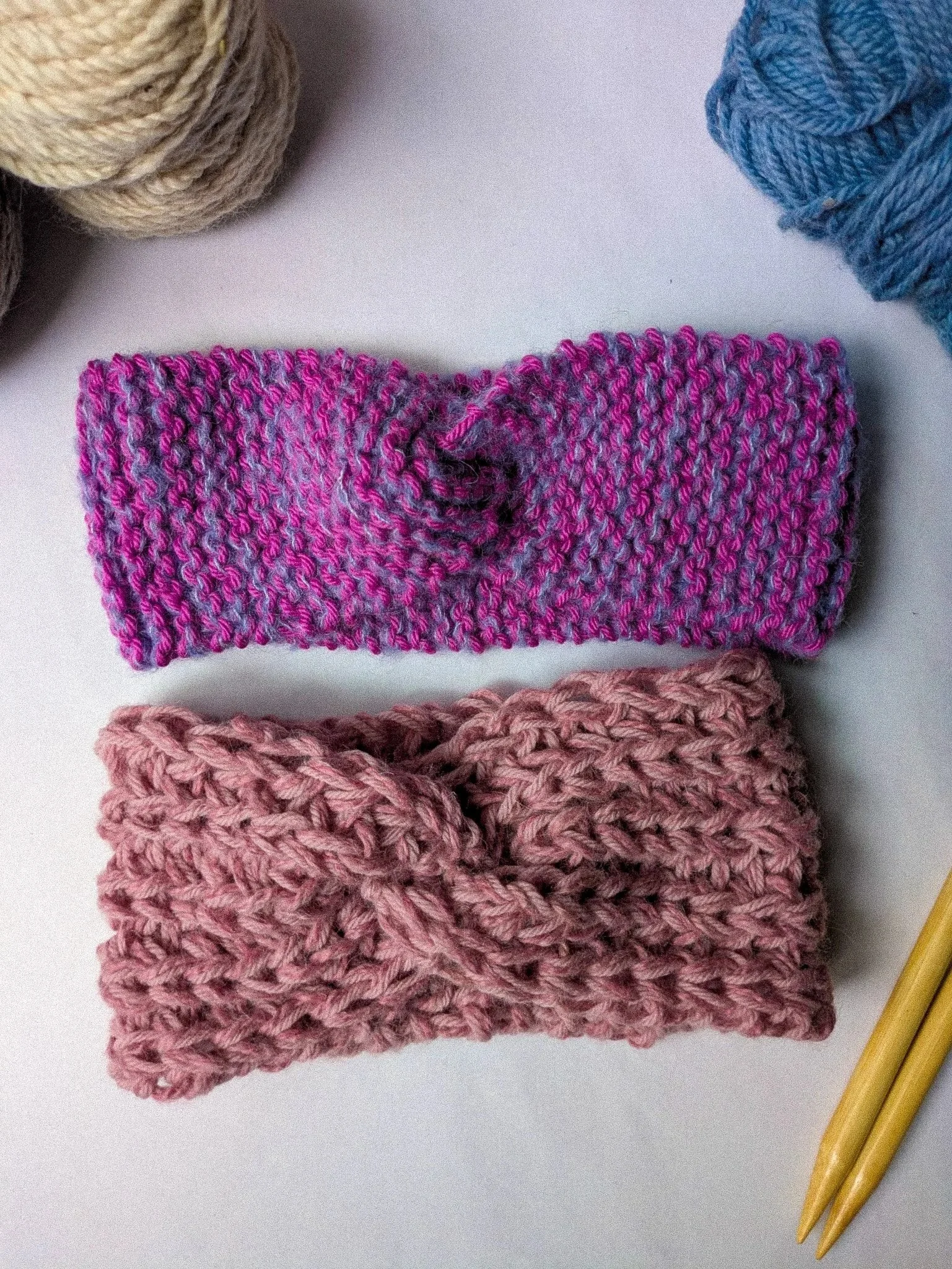 Two handknitted headbands lay on a white background