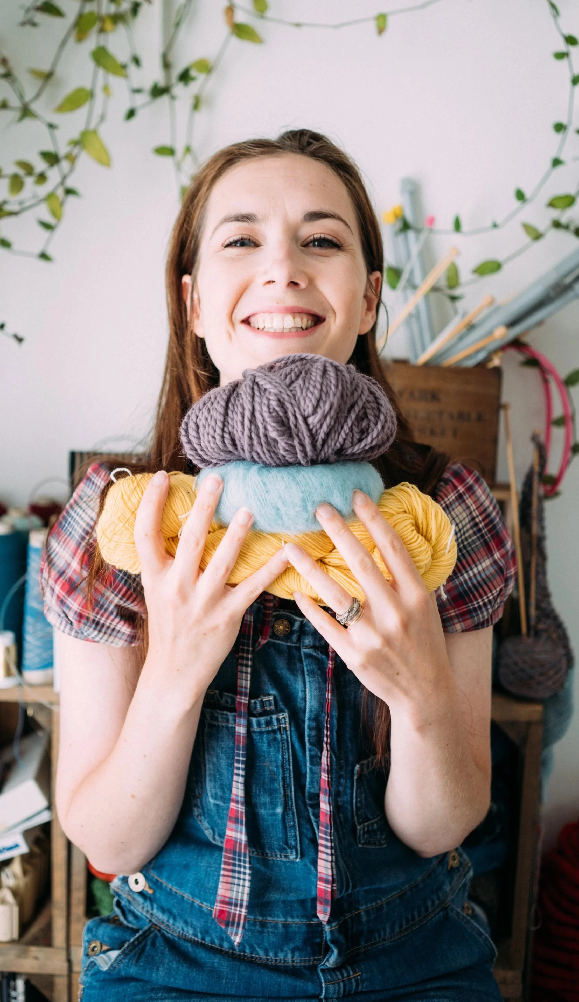Knitting Teacher Alice, a white woman holds 3 balls of yarn and smiles