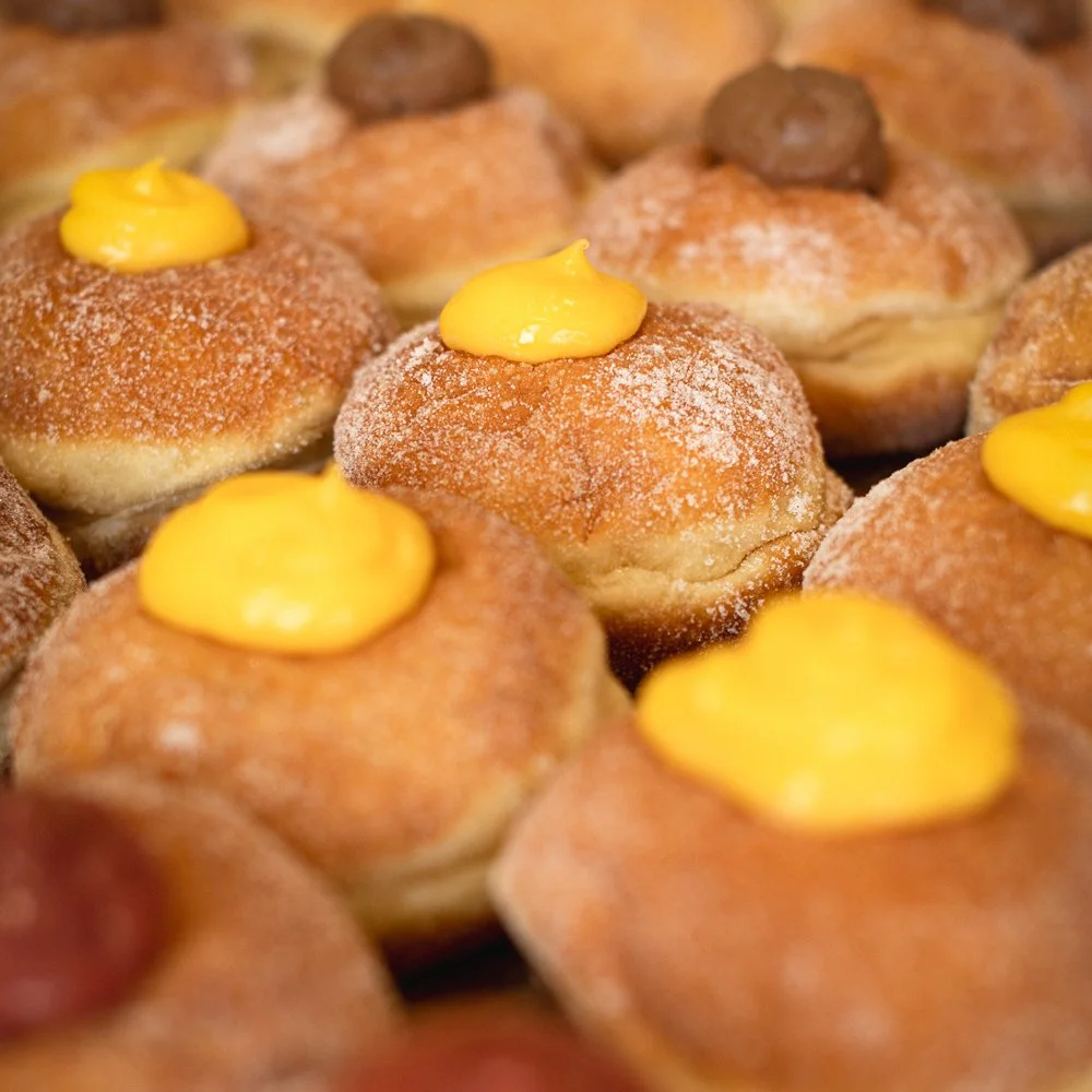 Close-up of donut holes topped with yellow custard or frosting and some with chocolate candies.