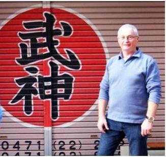 Man standing in front of a large sign with Japanese characters and a red circle.