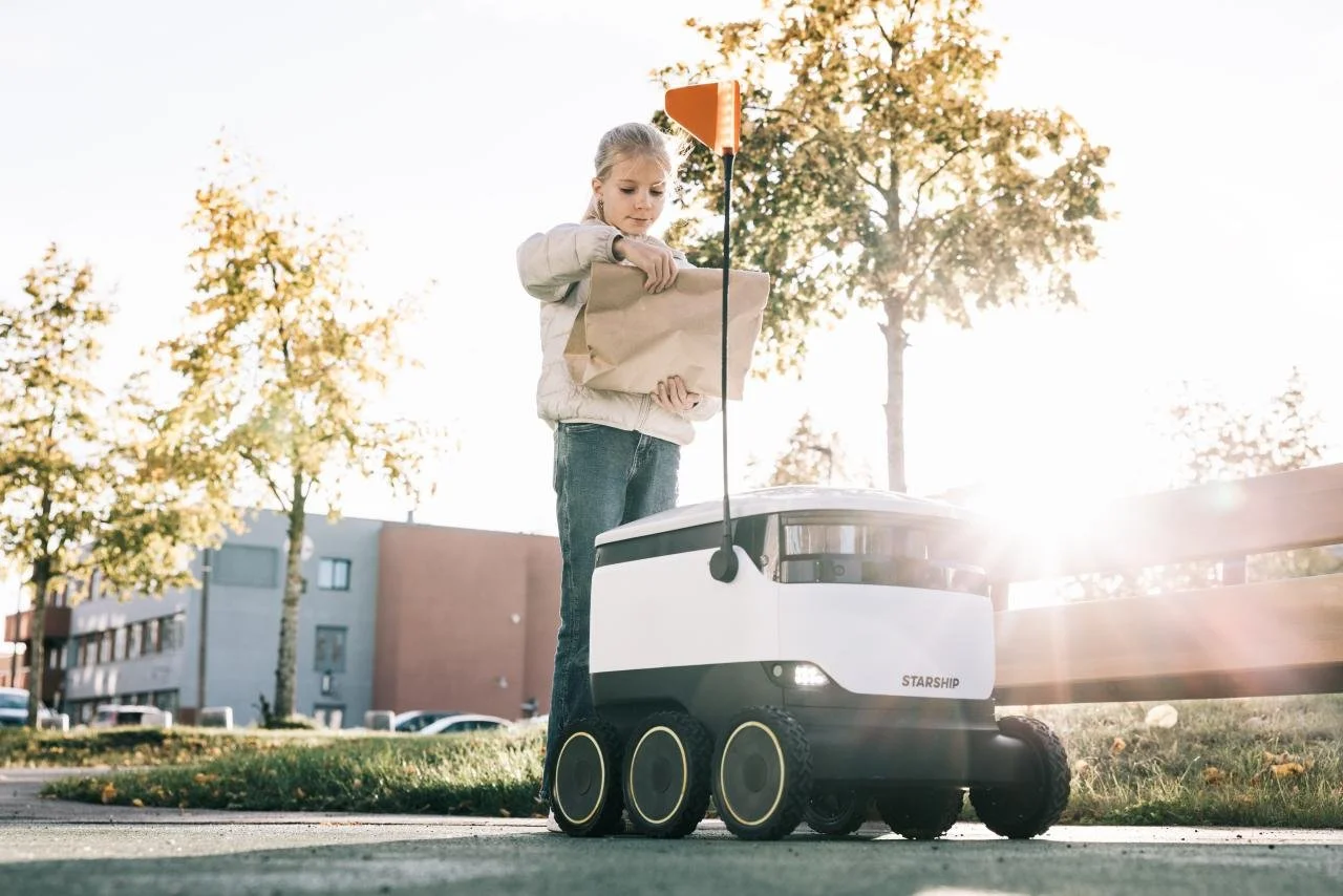 Girl receiving package from Starship robot.jpeg