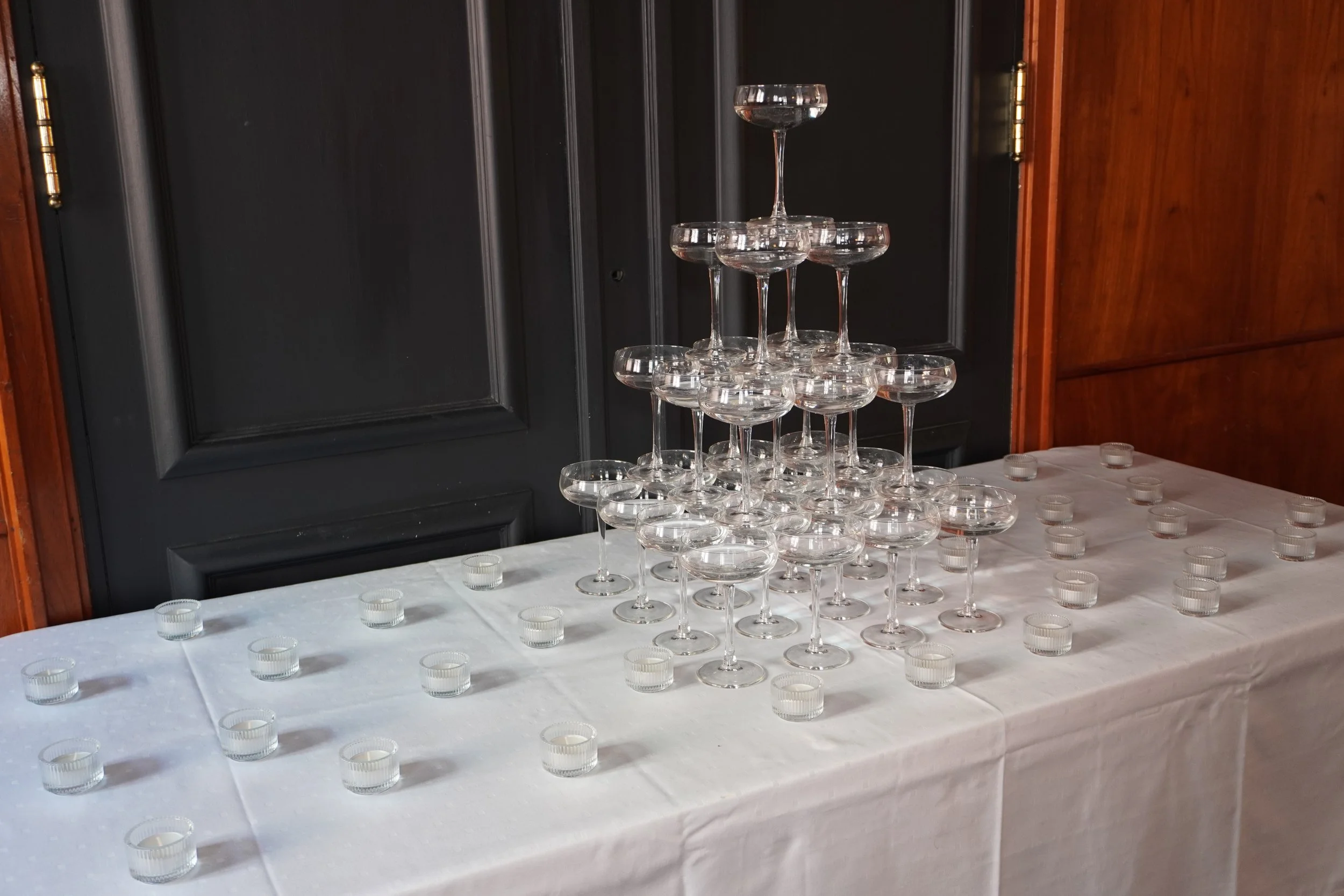 Lyst rom med 12 bord og stoler, stor projektor skjerm, nødvendig lydutstyr, tre store vinduer, mørkmalte vegger, tre taklys og en krone på taket.