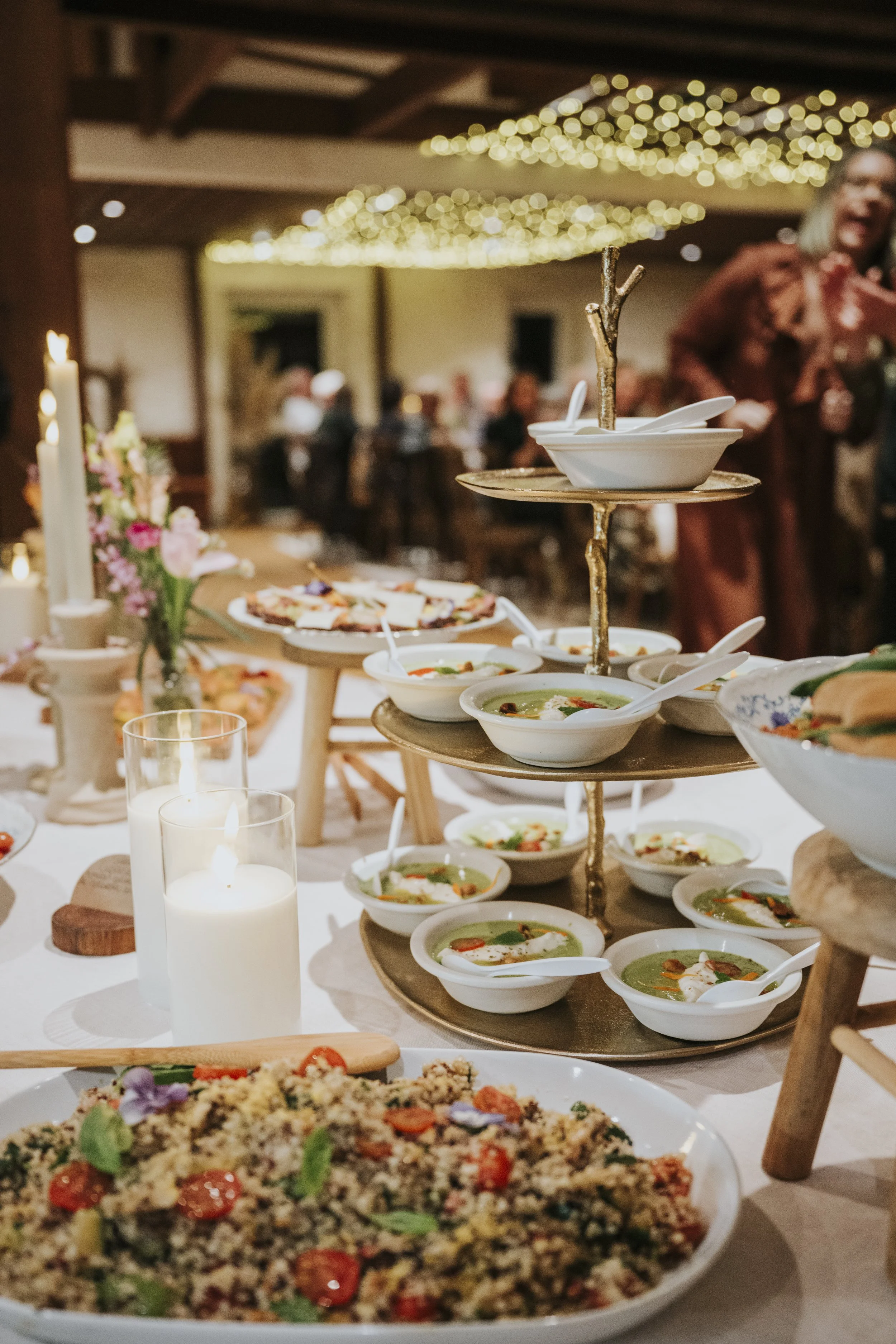 Table de fête avec plats, soupe, salade et bougies dans une ambiance chaleureuse.