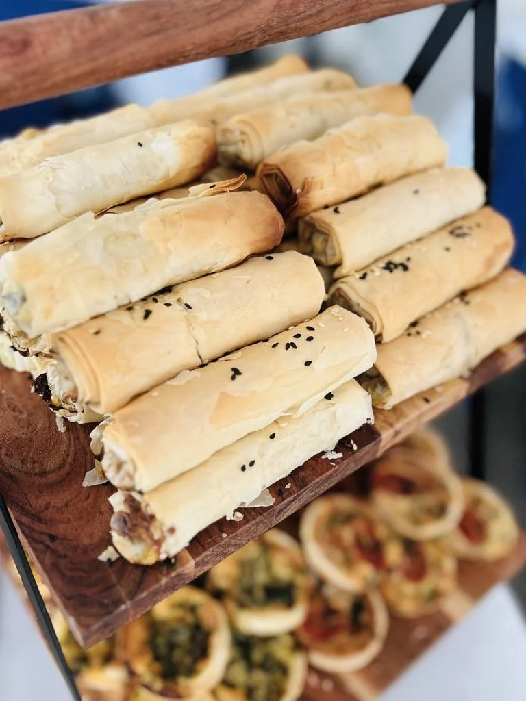 A tiered display of layered spring rolls with a golden-brown crispy exterior and black sesame seeds on top.