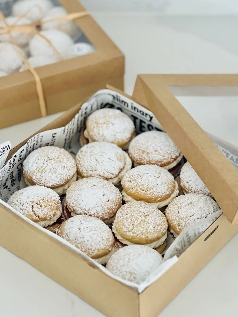 A box of assorted sandwich cookies with powdered sugar topping.