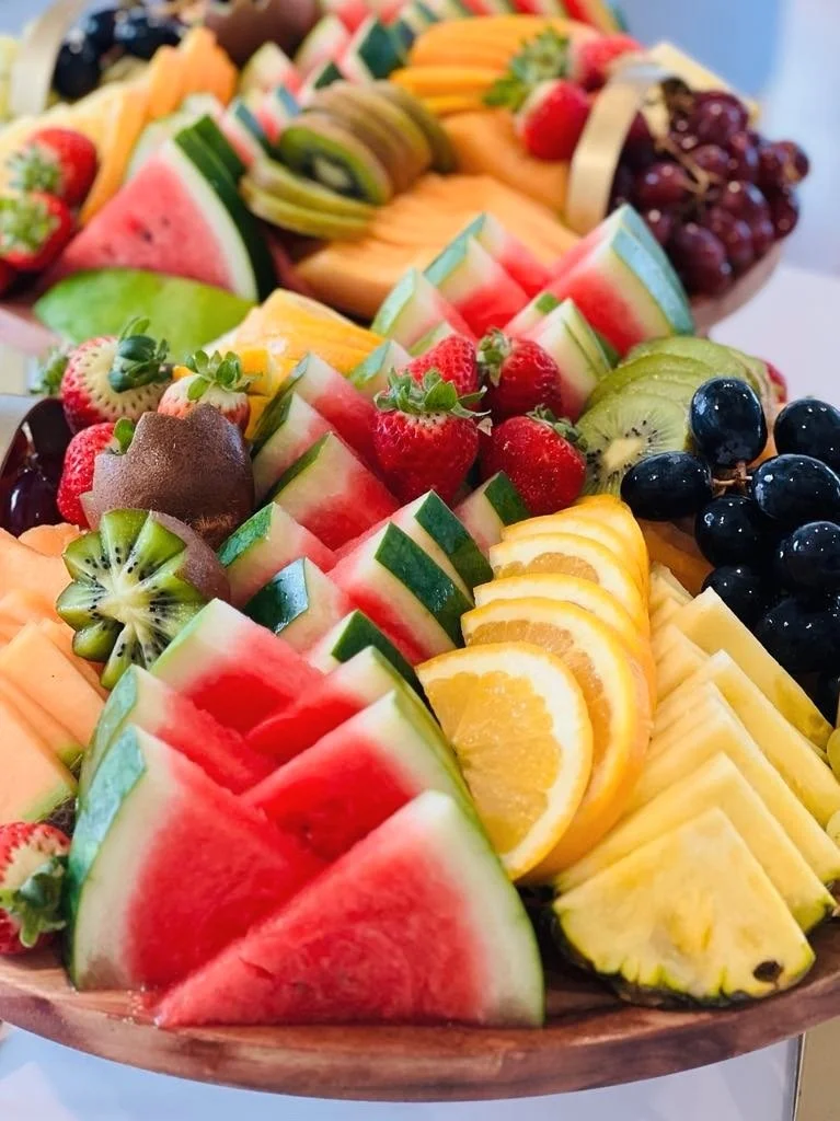 Assorted sliced fresh fruits, including watermelon, strawberries, kiwi, pineapple, orange, grapes, honeydew, and cantaloupe on a platter.