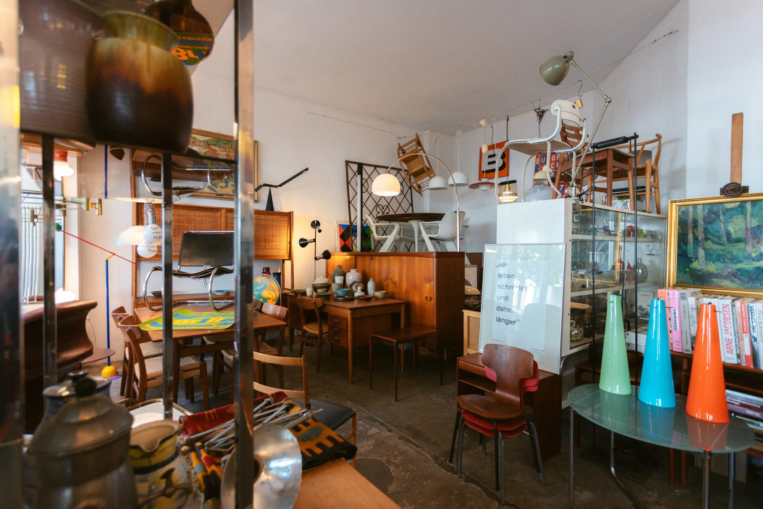 Ein chaotischer Raum mit Möbeln, Vasen, Büchern, Gemälden und mehreren upgecycelten Stühlen, die an der Decke gestapelt sind.