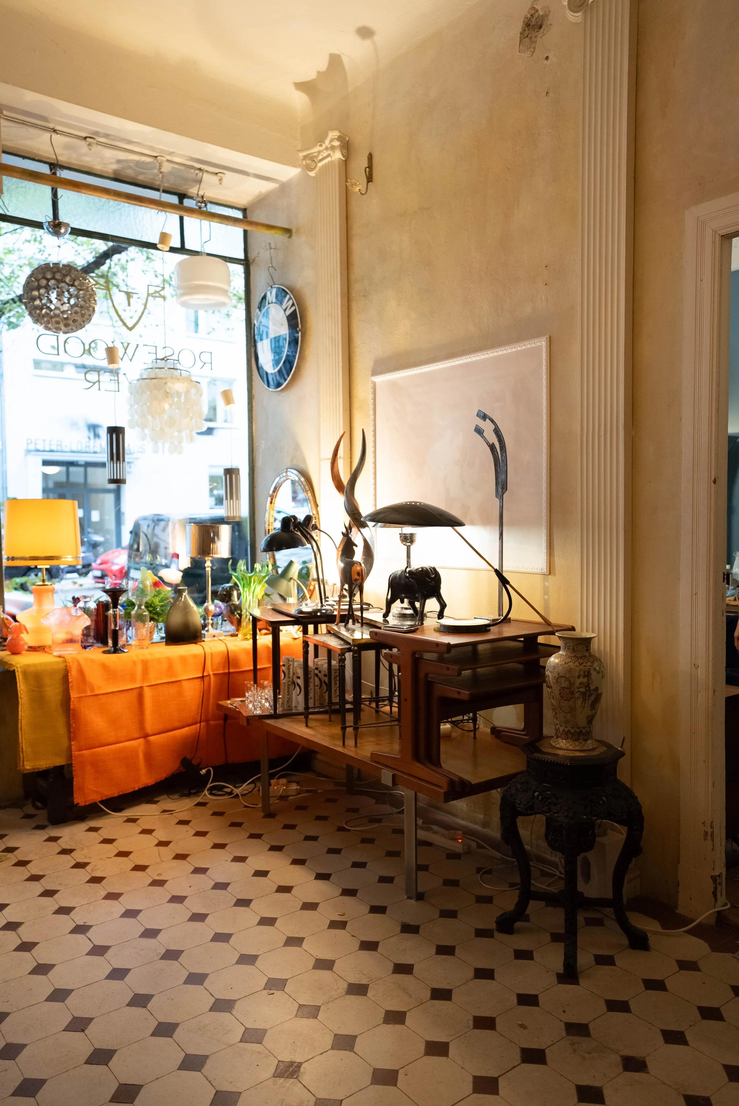 Inneneinrichtung mit dekorativen Gegenständen, Lampen, Uhren, und Pflanzen, vor einem großen Fenster