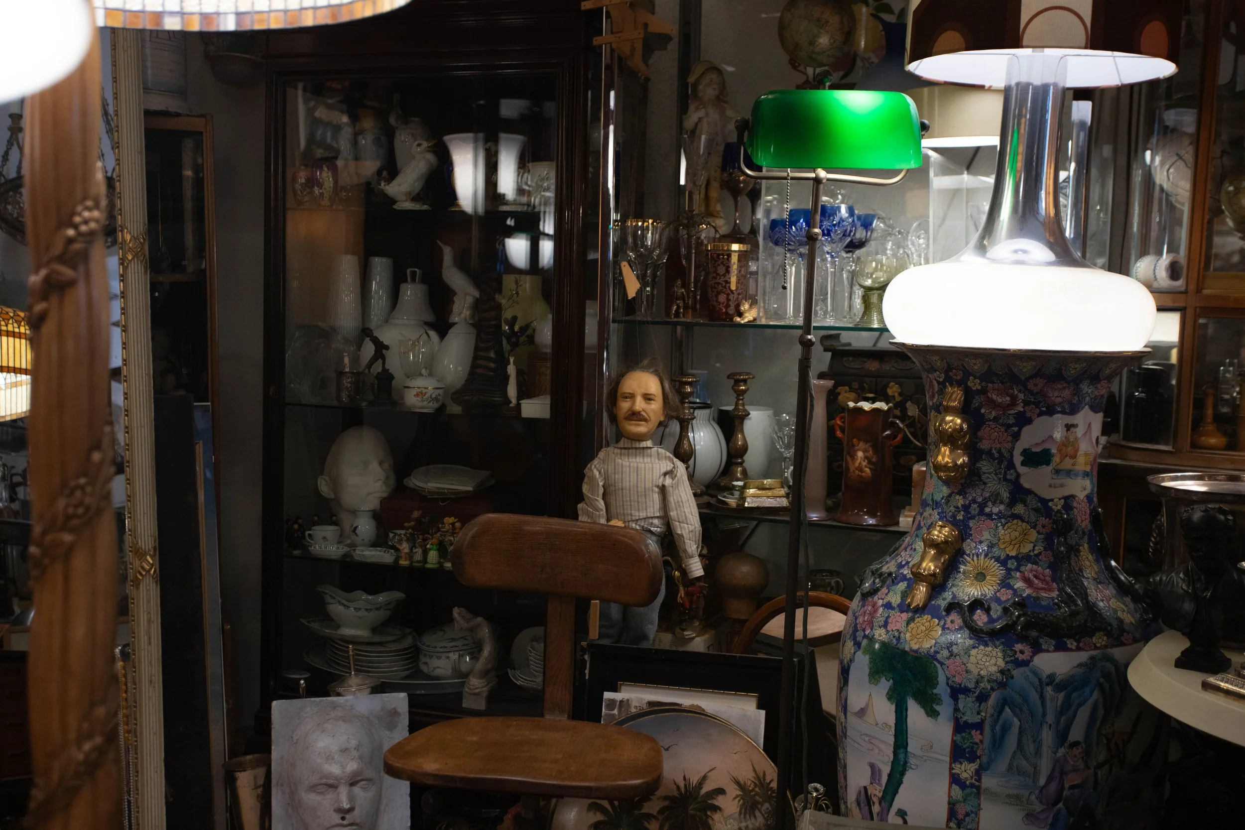 Ein Antiquitätengeschäft mit verschiedenen alten Gegenständen, darunter eine Puppe, Vasen, Gläser, Lampen und Skulpturen.