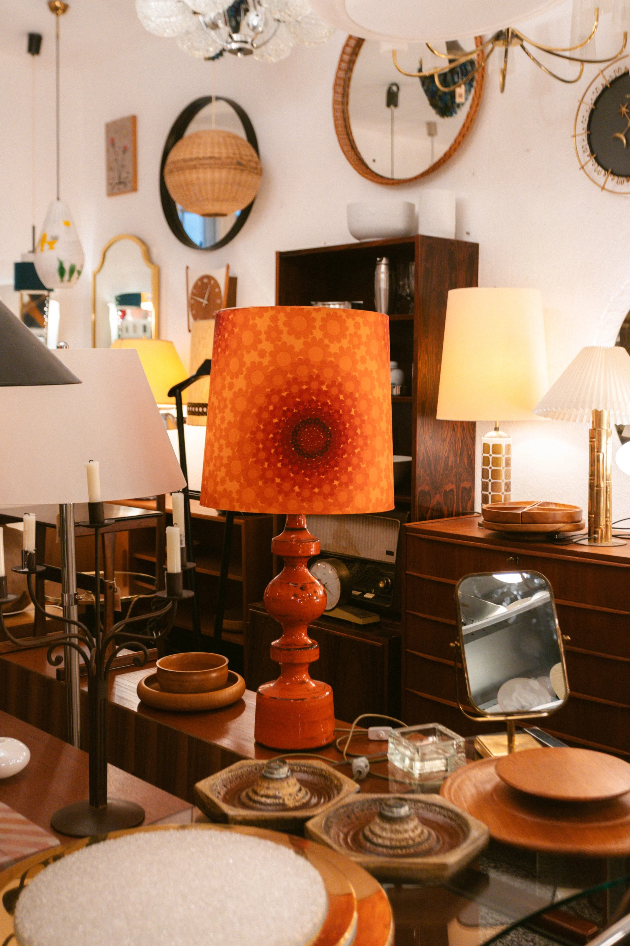 Ein Wohnzimmer mit verschiedenen Lampen, Wanduhren, Spiegeln und Holzmöbeln, dekoriert im Retro-Stil.