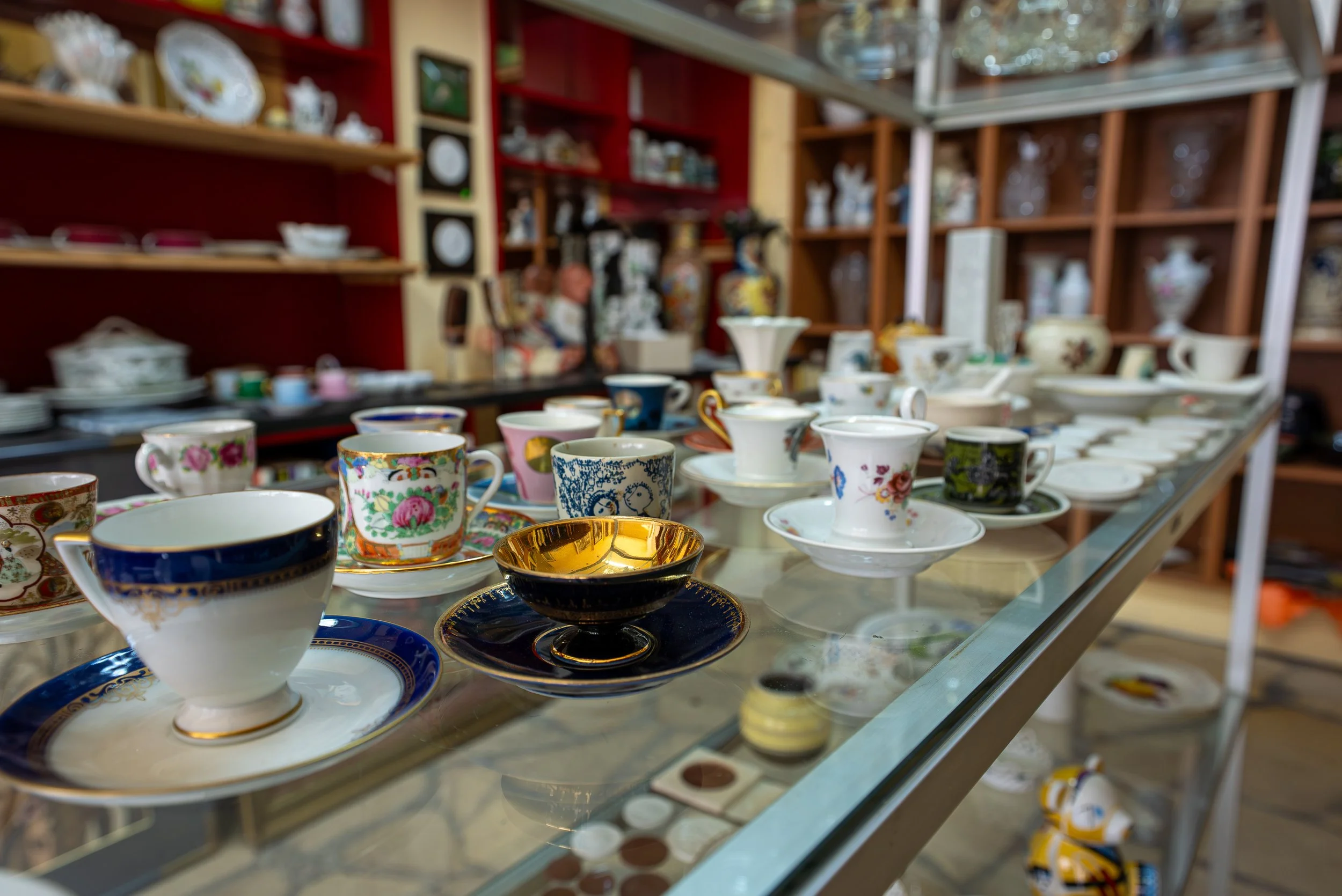 Verschiedene Porzellantassen und -untere in einem Ausstellungsregal, typisch für ein Geschäft für Porzellan.