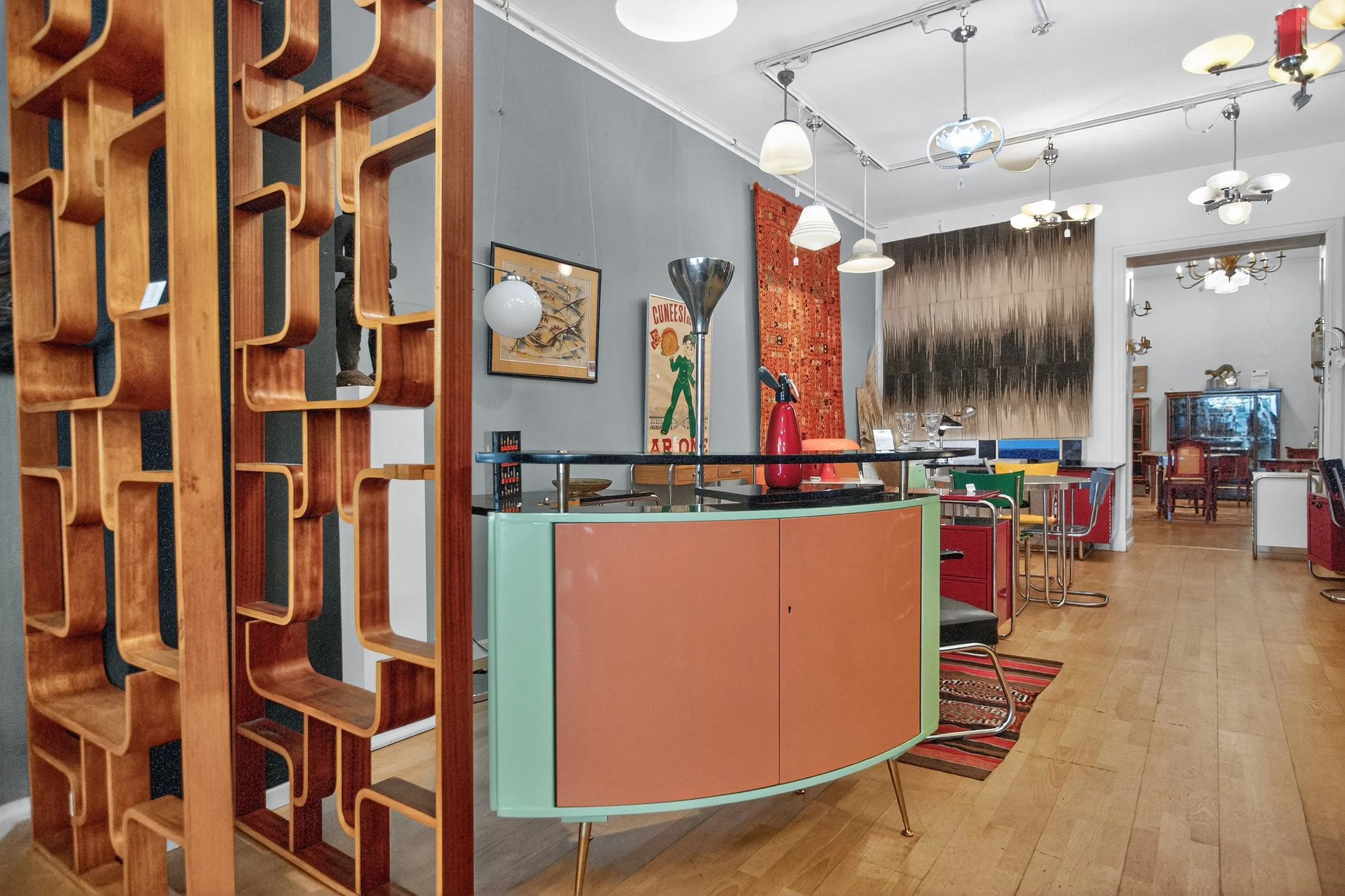 Innenansicht eines stilvollen Wohn- oder Gemeinschaftsraums mit bunten Möbeln, kunstvollen Dekorationen und verschiedenen Leuchten.