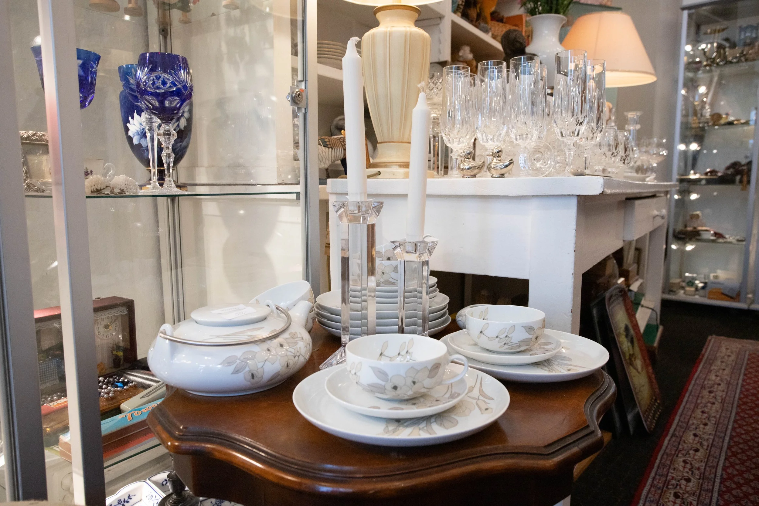 Verschiedene antike Keramik- und Glasscherzen, einschließlich Teller, Schalen, Kerzenhalter, Vasen und Trinkgläser, in einem Möbelgeschäft aufgestellt.