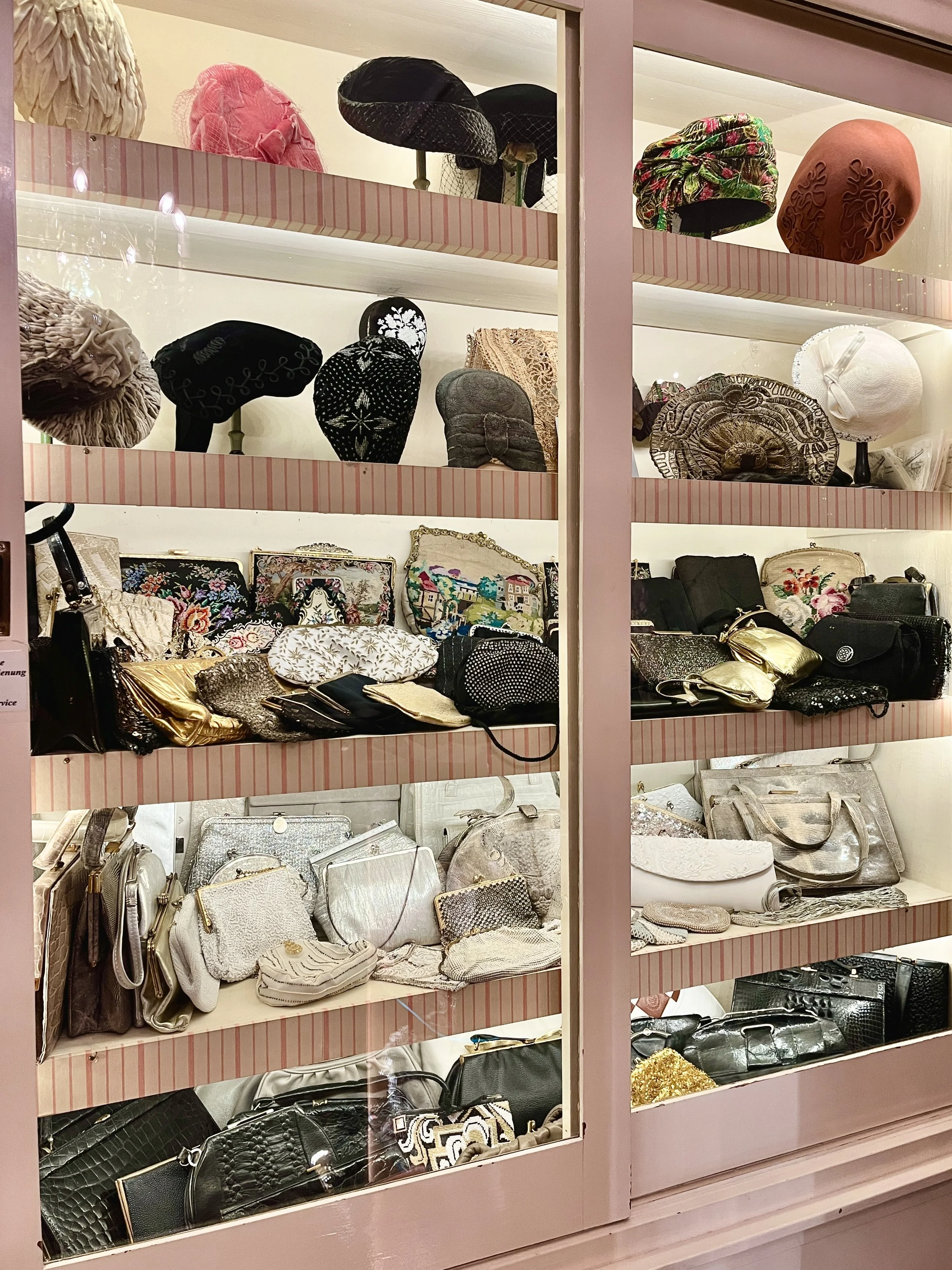 Verschiedene Handtaschen, Geldbörsen und Clutches auf vier Regalen in einem Schaufenster display.