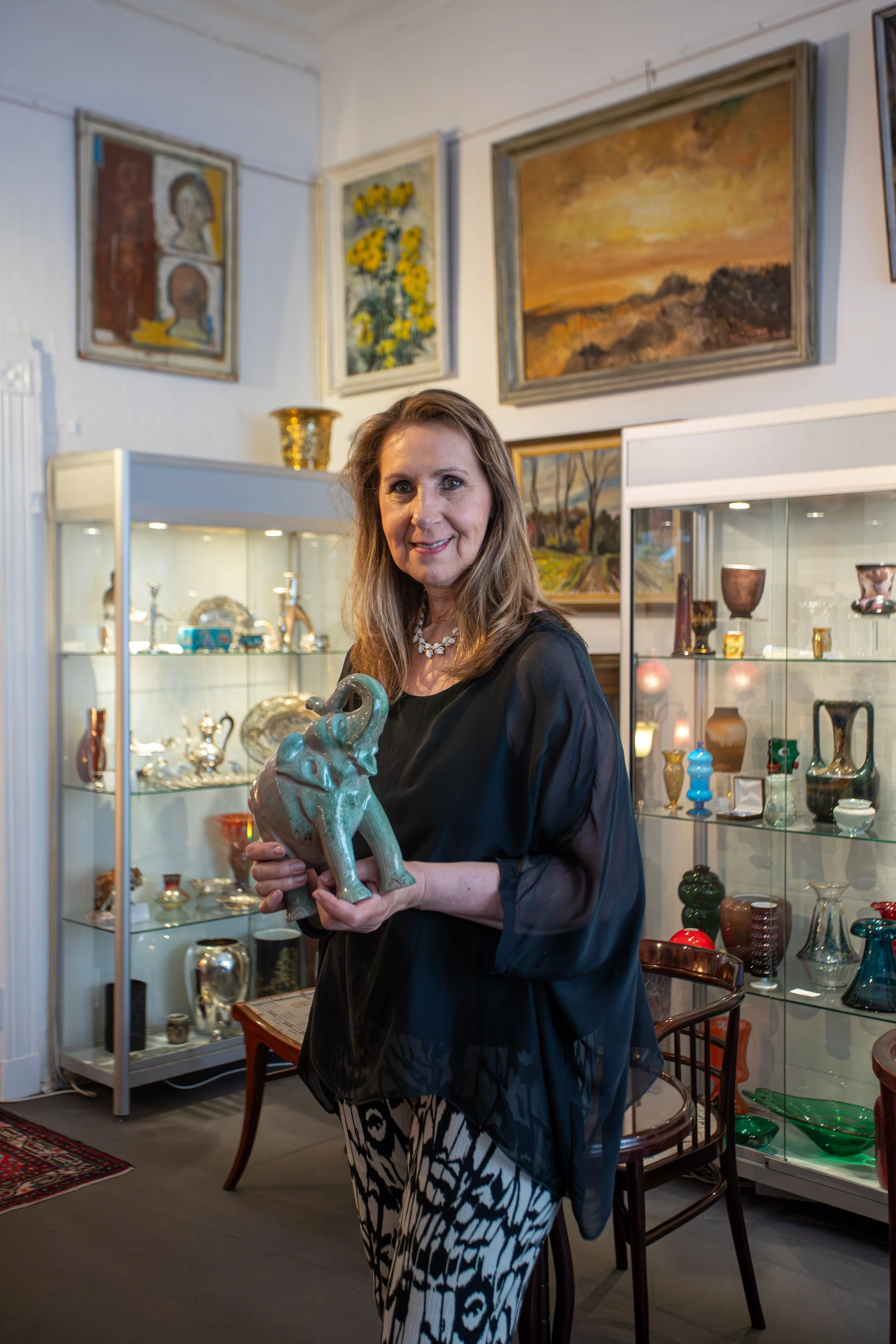 Frau in schwarzem Kleid, die eine Elefantenstatue in einem Kunsthandwerksladen hält.