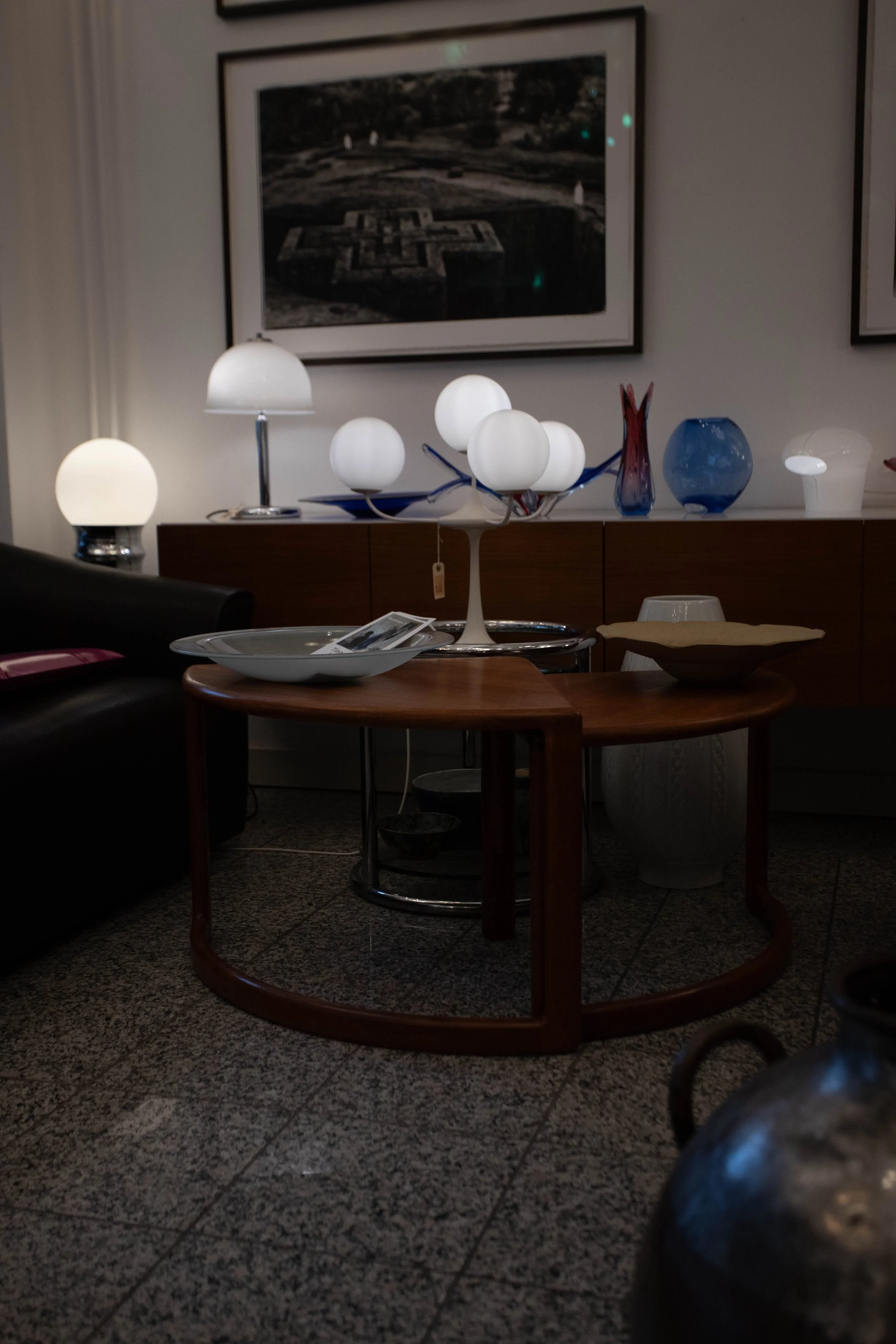 Wohnzimmer mit Stehlampen, Sofa, Kaffeetisch, dekorative Vasen auf einer Kommode und einem Wandbild