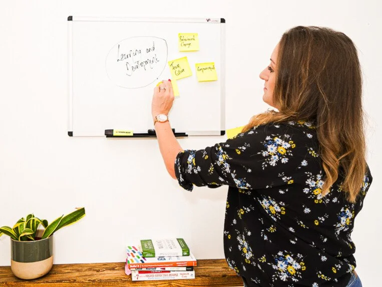 Image of Livvy place yellow post-it notes on whiteboard